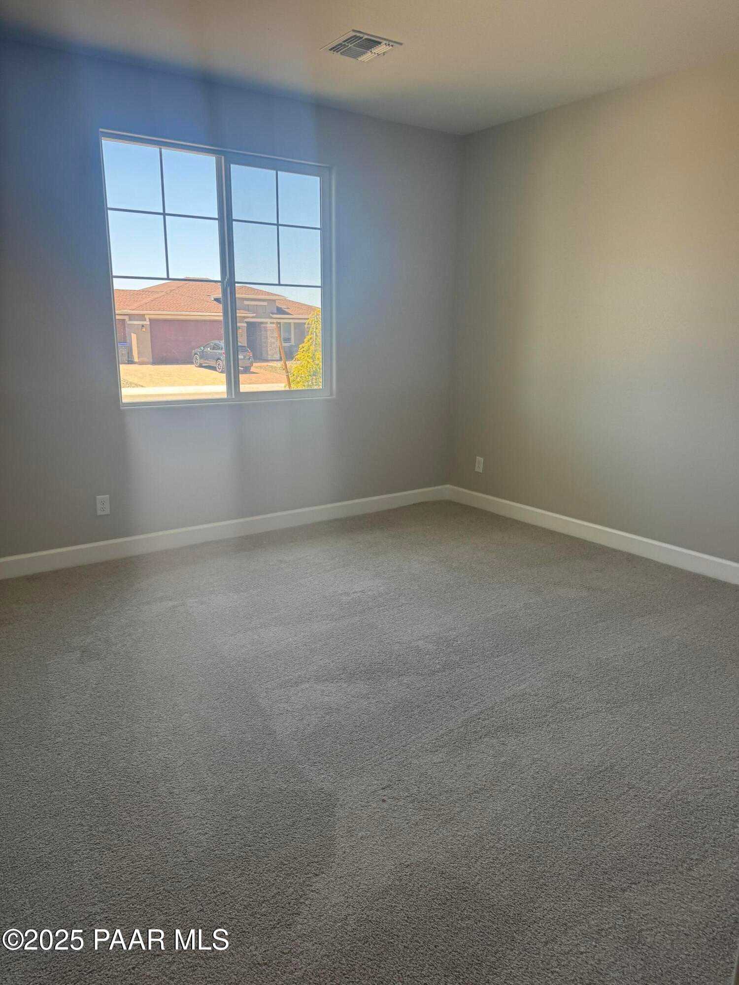 Bright empty bedroom with large window overlooking desert neighborhood in Evermore Homes The Summit B, Prescott Valley, Arizona