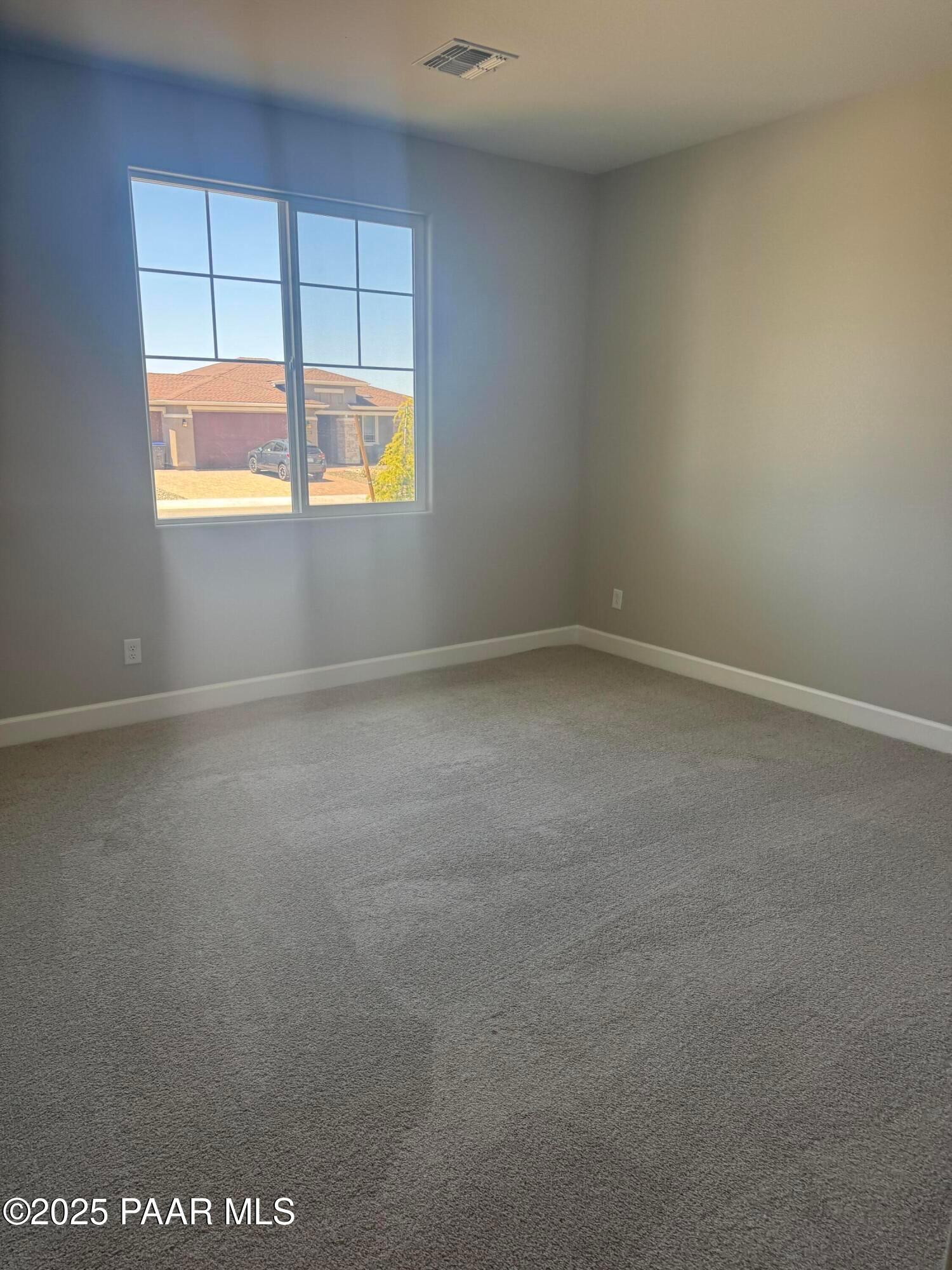 Bright empty bedroom with large window overlooking desert neighborhood in Evermore Homes The Summit B, Prescott Valley, Arizona