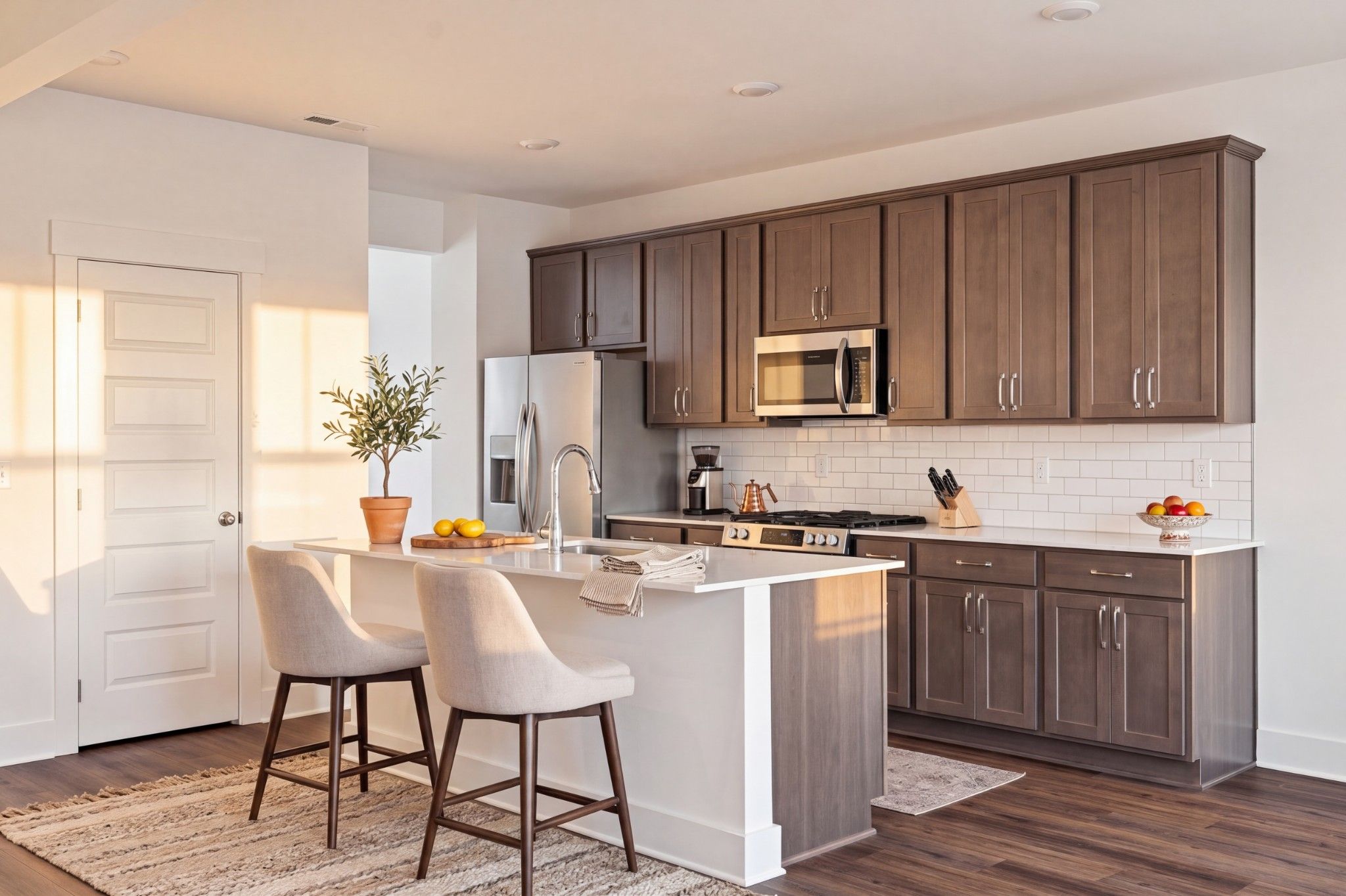Modern kitchen with dark wood cabinets, white island with bar stools, and stainless appliances in Davidson Homes Willow C plan, Gallatin TN