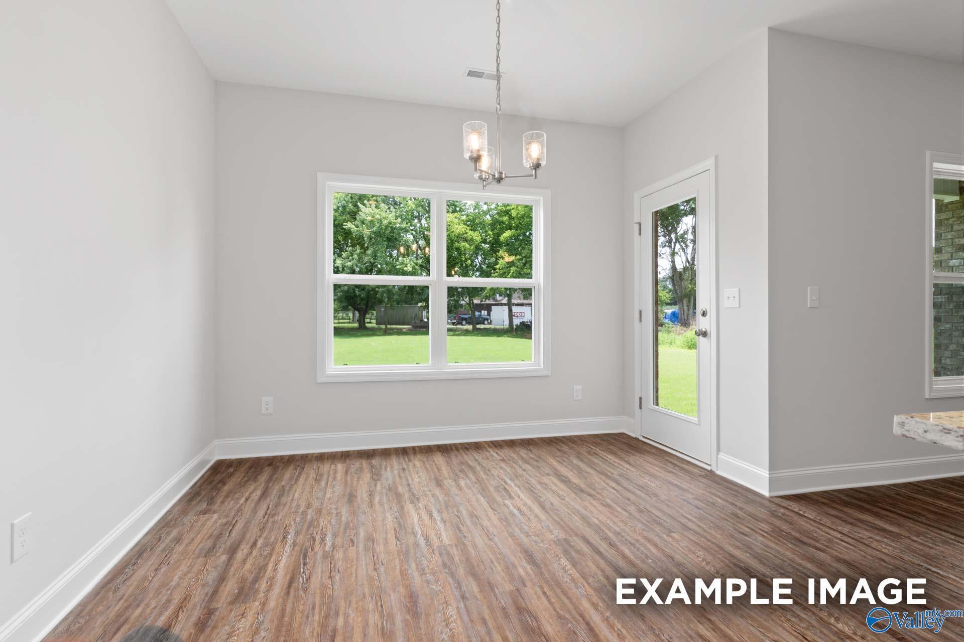 Bright dining area with luxury vinyl plank flooring, chandelier, and backyard views in Davidson Homes The Asheville C, Huntsville