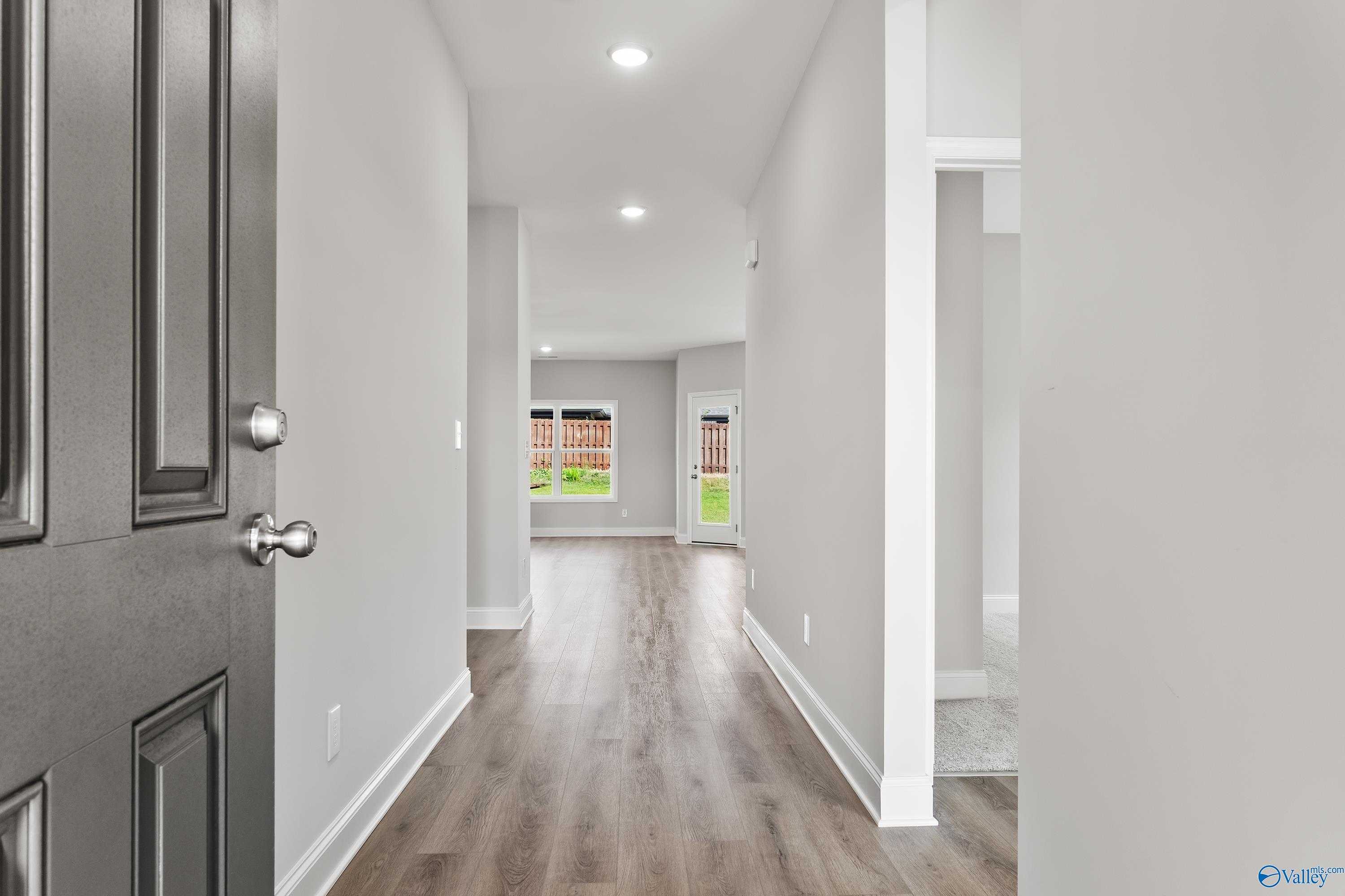 Spacious entry hallway with luxury vinyl plank flooring, open front door, and natural light in Davidson Homes The Franklin C, Toney, Alabama