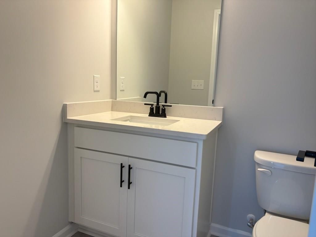 Modern bathroom featuring white shaker vanity, black faucet, mirror, and elongated toilet in Davidson Homes The Hickory B, Winder, GA