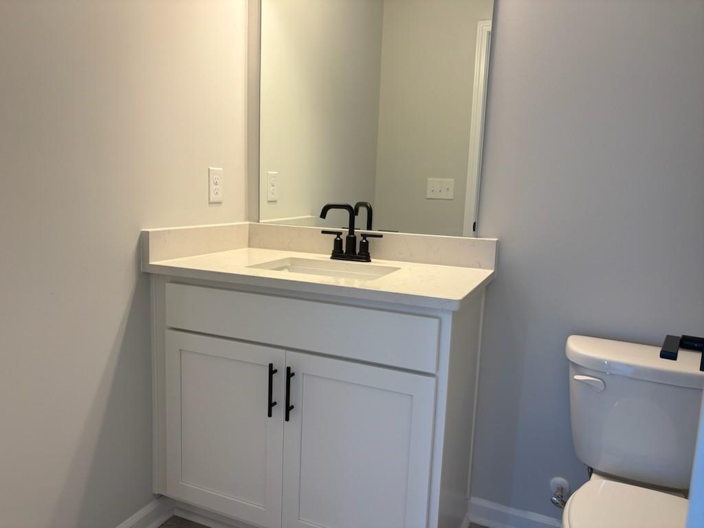 Modern bathroom featuring white shaker vanity, black faucet, mirror, and elongated toilet in Davidson Homes The Hickory B, Winder, GA