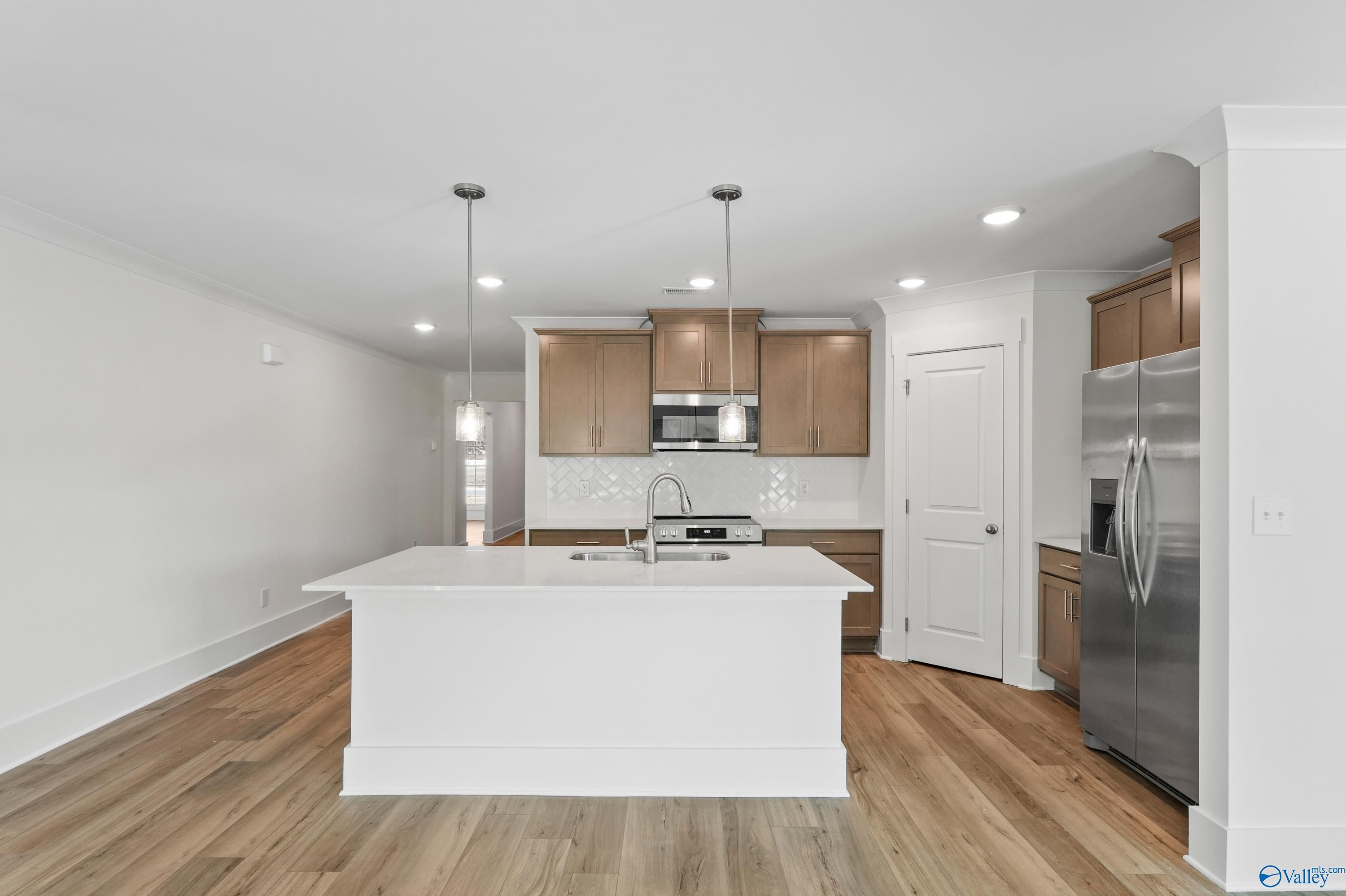 Modern kitchen with white island, shaker cabinets, stainless fridge in The Daphne C by Davidson Homes, Arab, Alabama