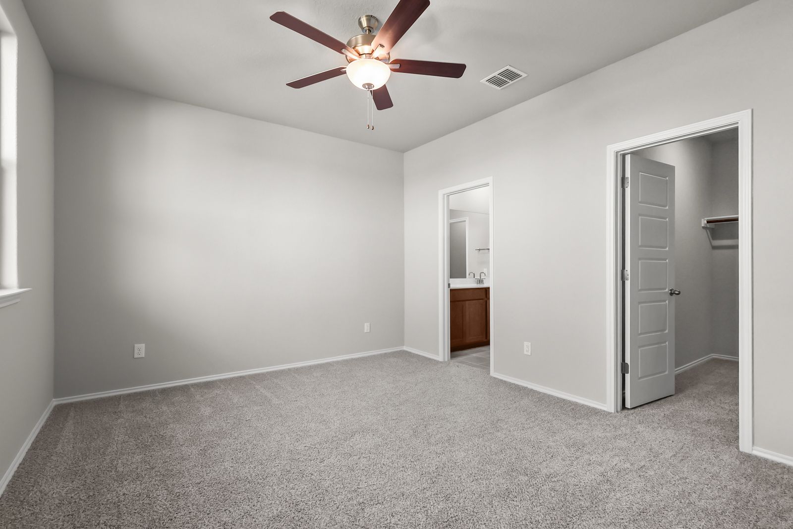 Spacious master bedroom in The Arroyo A featuring neutral carpet, ceiling fan, ensuite bathroom, and walk-in closet.