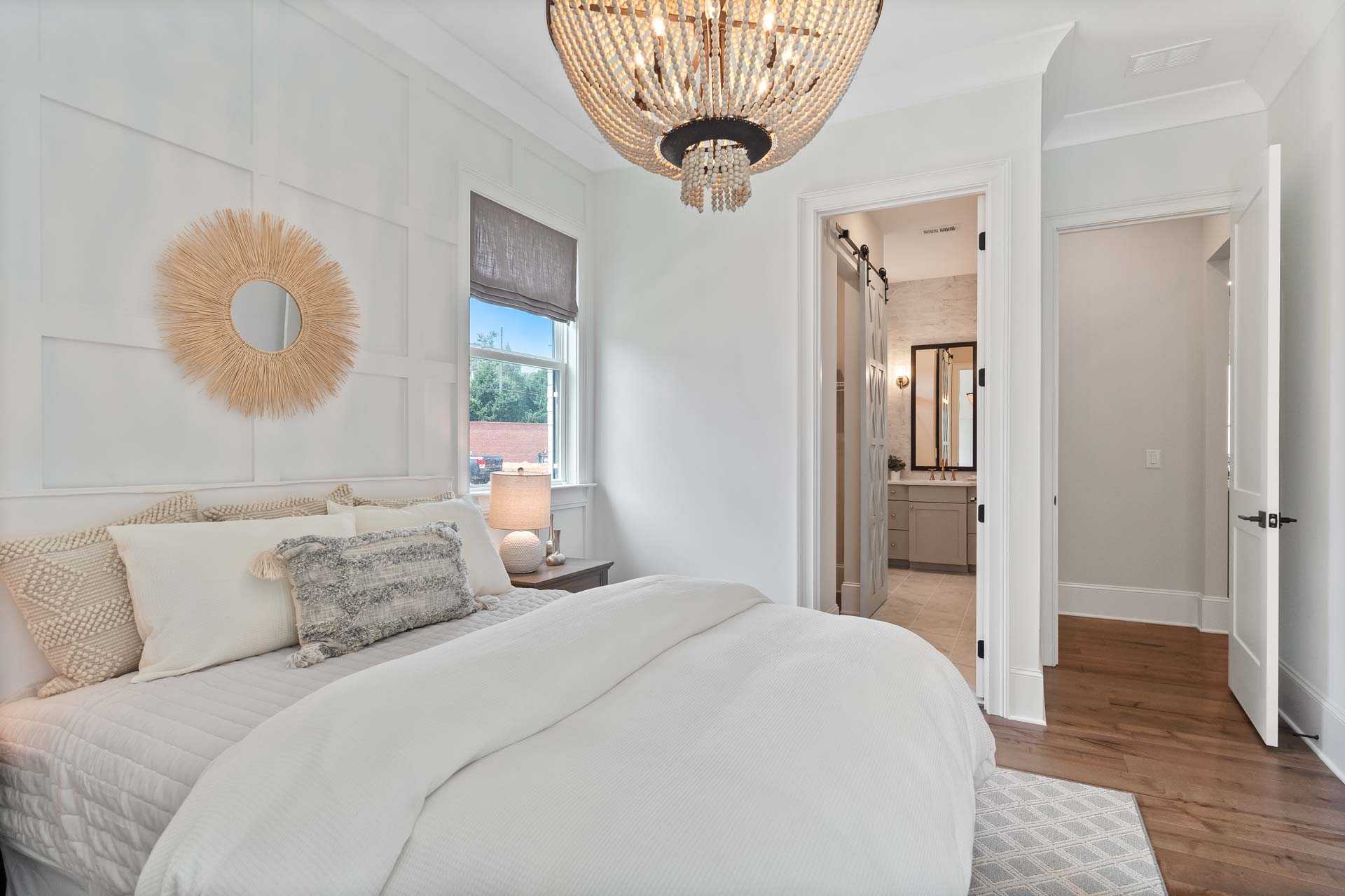 Cozy bedroom in Tanglewood East Cobb Georgia with white shiplap walls beaded chandelier king bed and en-suite bathroom
