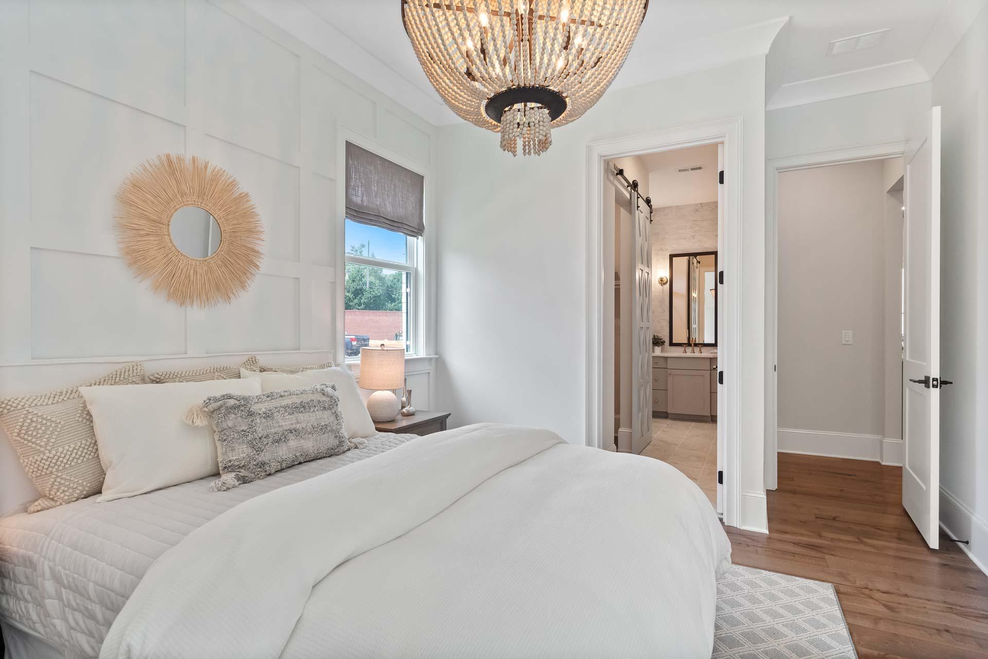 Cozy bedroom in Tanglewood East Cobb Georgia with white shiplap walls beaded chandelier king bed and en-suite bathroom