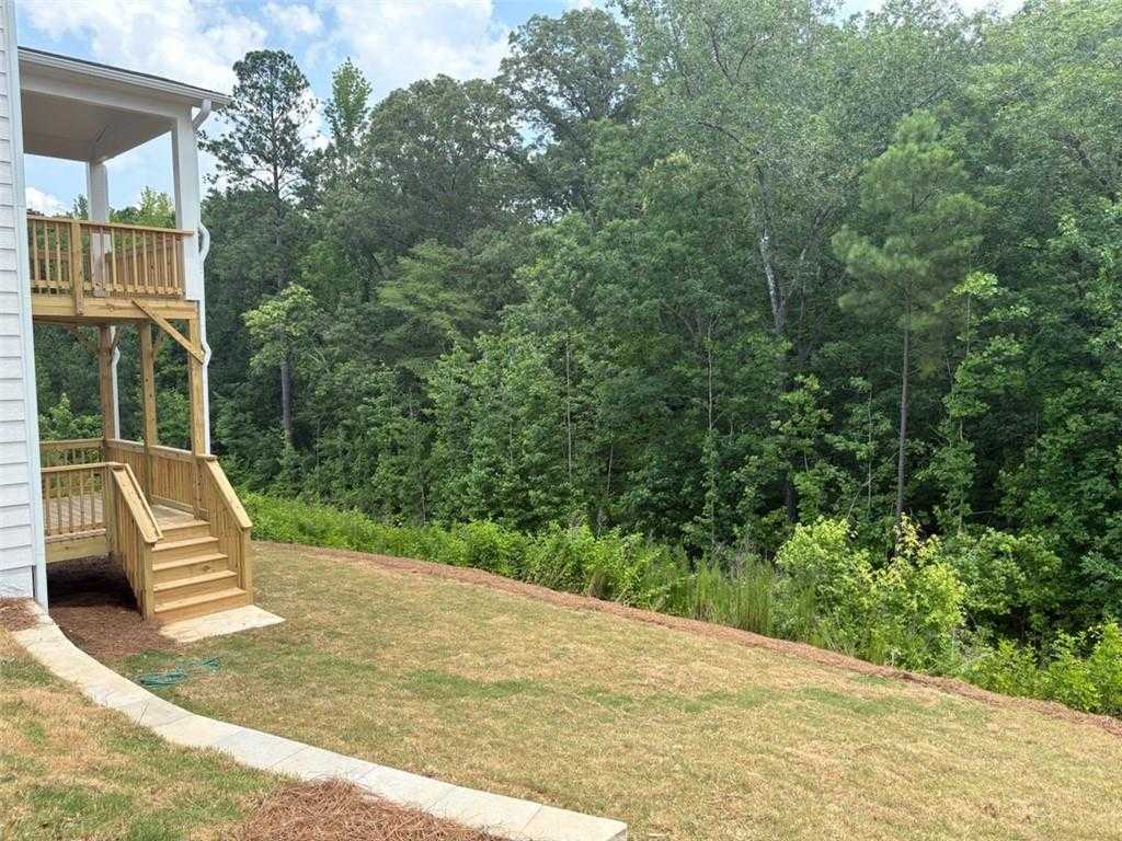 Two-story Davidson Homes exterior with wooden upper deck, stairs, and lush wooded backyard in Riverwood, Dallas, Georgia