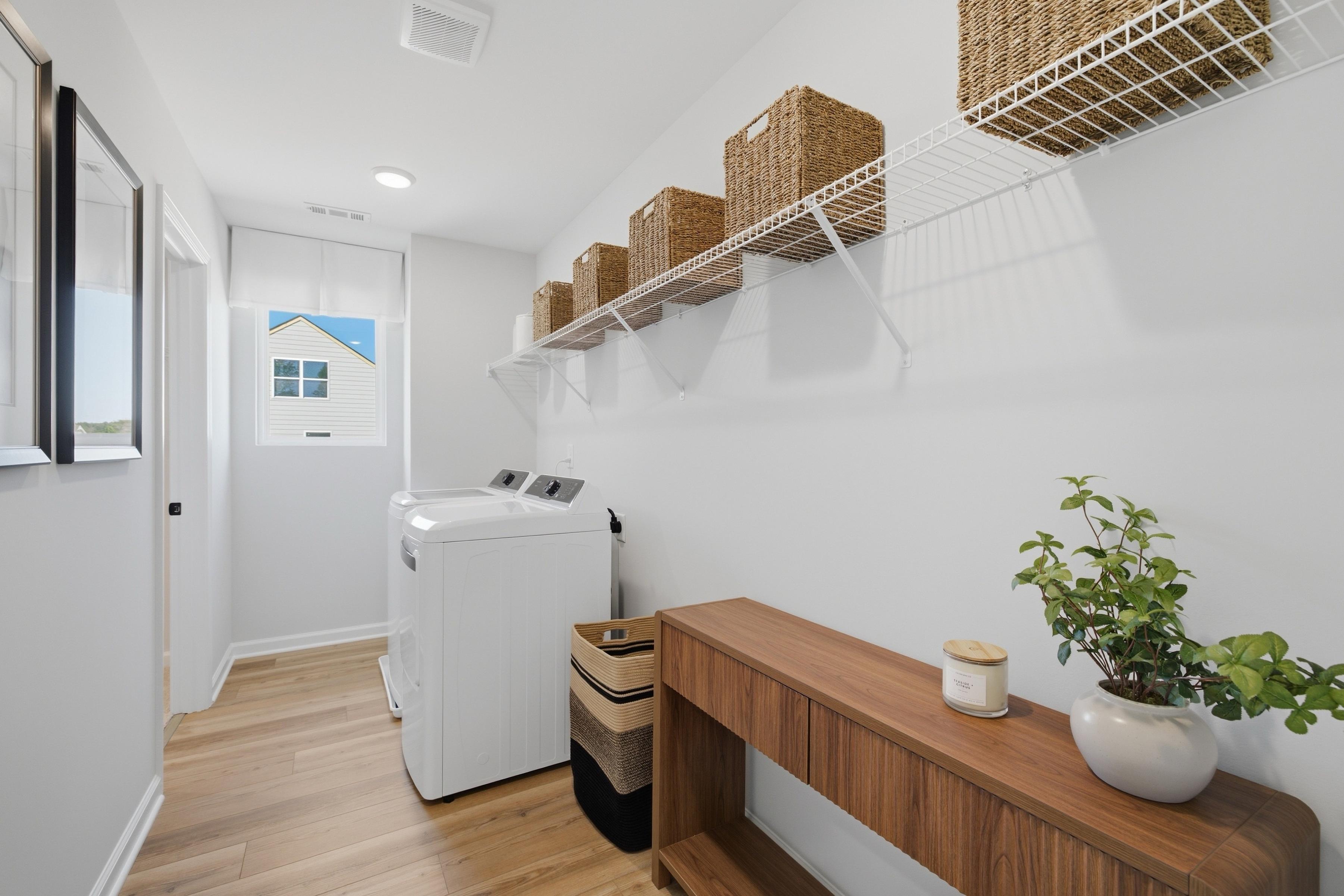 Bright laundry room at Greene Farm in Cartersville, GA by Davidson Homes with washer, dryer, wood floors, and storage shelves