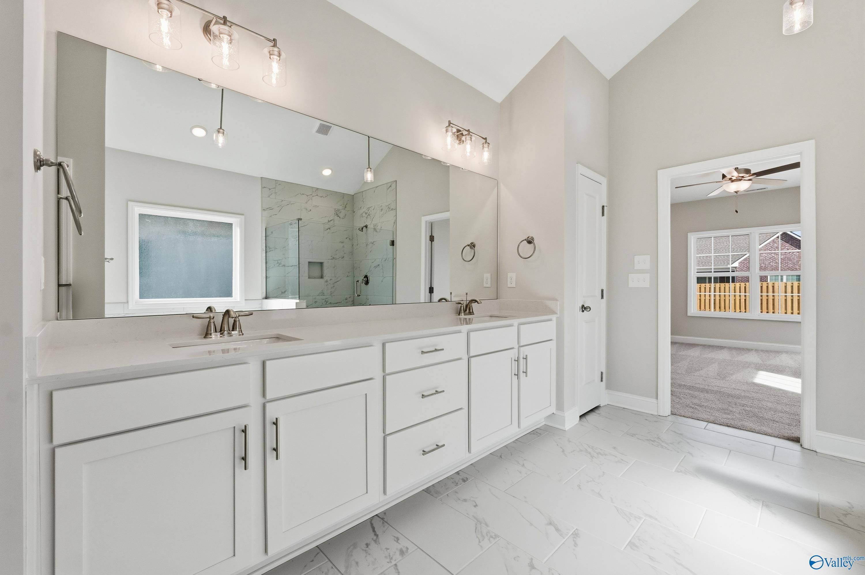 Elegant master bathroom featuring double vanity, white cabinets, glass shower, and neutral tones in Davidson Homes The Finleigh, Harvest, AL