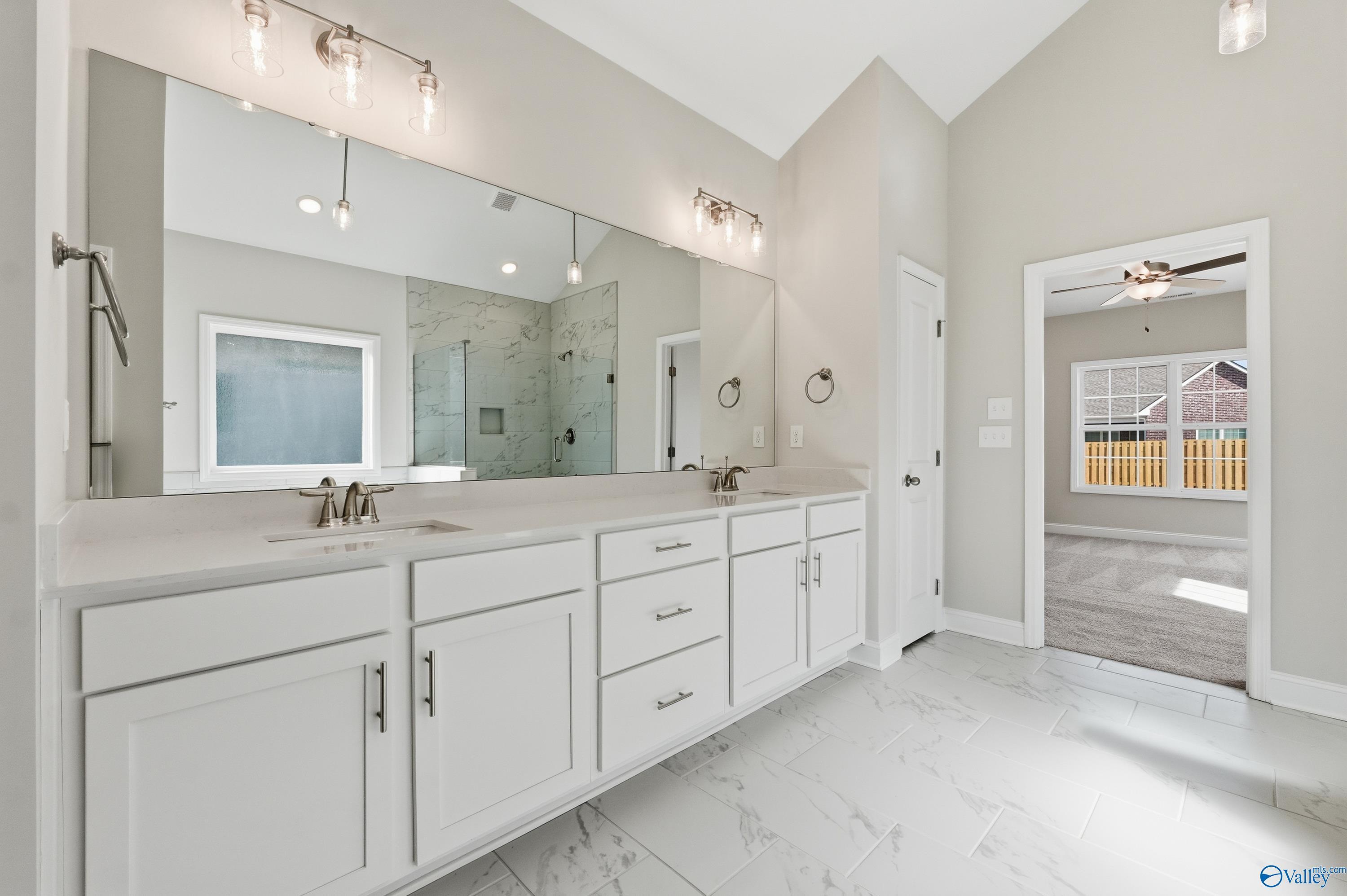 Elegant master bathroom featuring double vanity, white cabinets, glass shower, and neutral tones in Davidson Homes The Finleigh, Harvest, AL