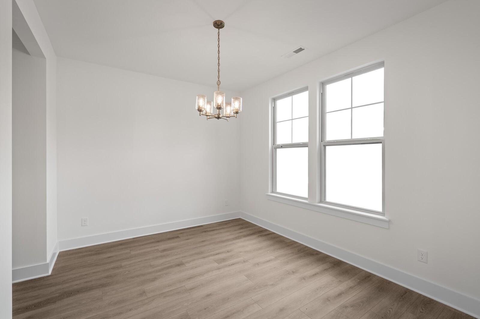 Bright dining room with 5-light chandelier, large windows, hardwood floors in Davidson Homes The Willow C, Gallatin, TN