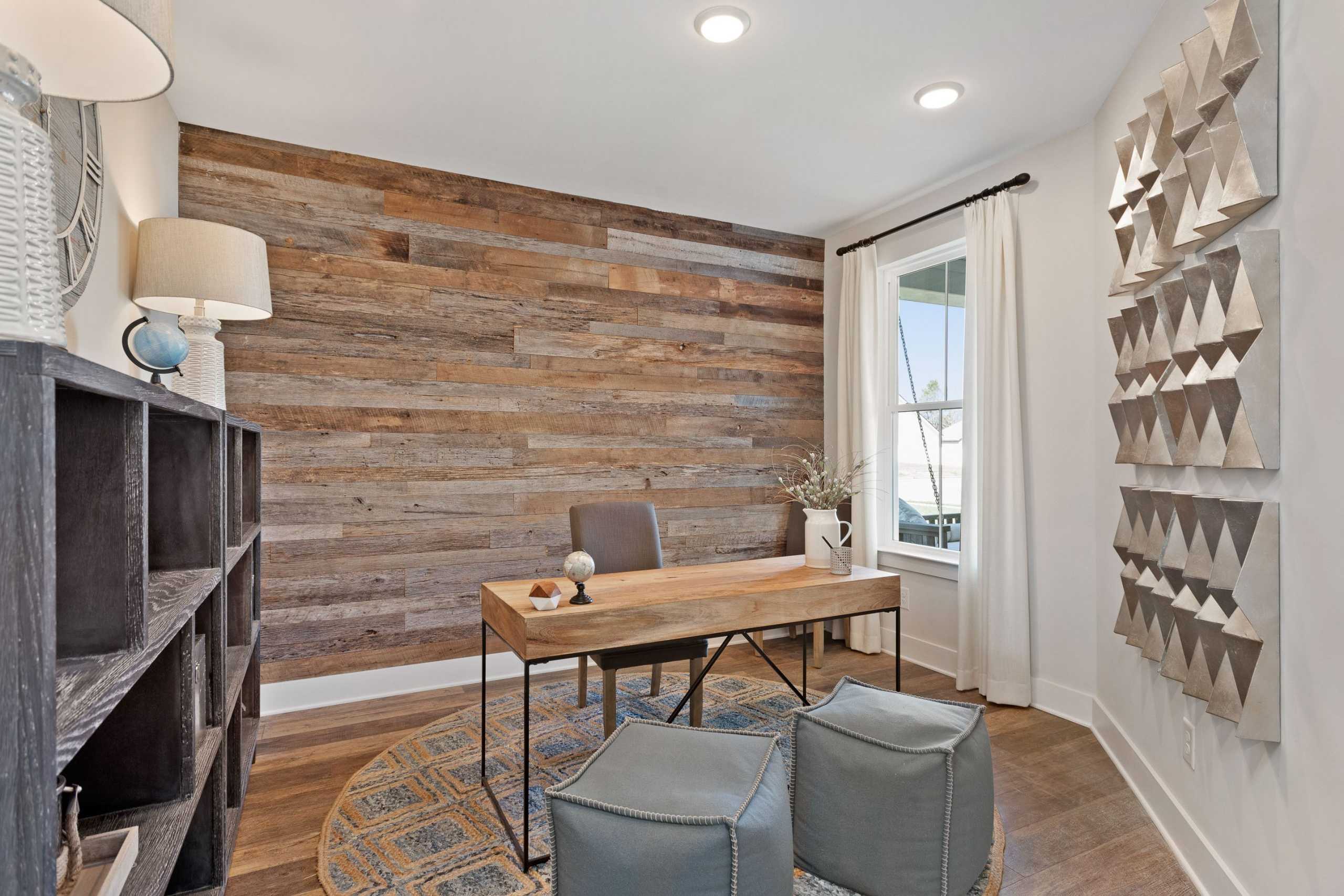 Cozy home office at Rivers Edge in Murfreesboro TN featuring reclaimed wood accent wall, wooden desk, bookshelves and geometric art by Davidson Homes