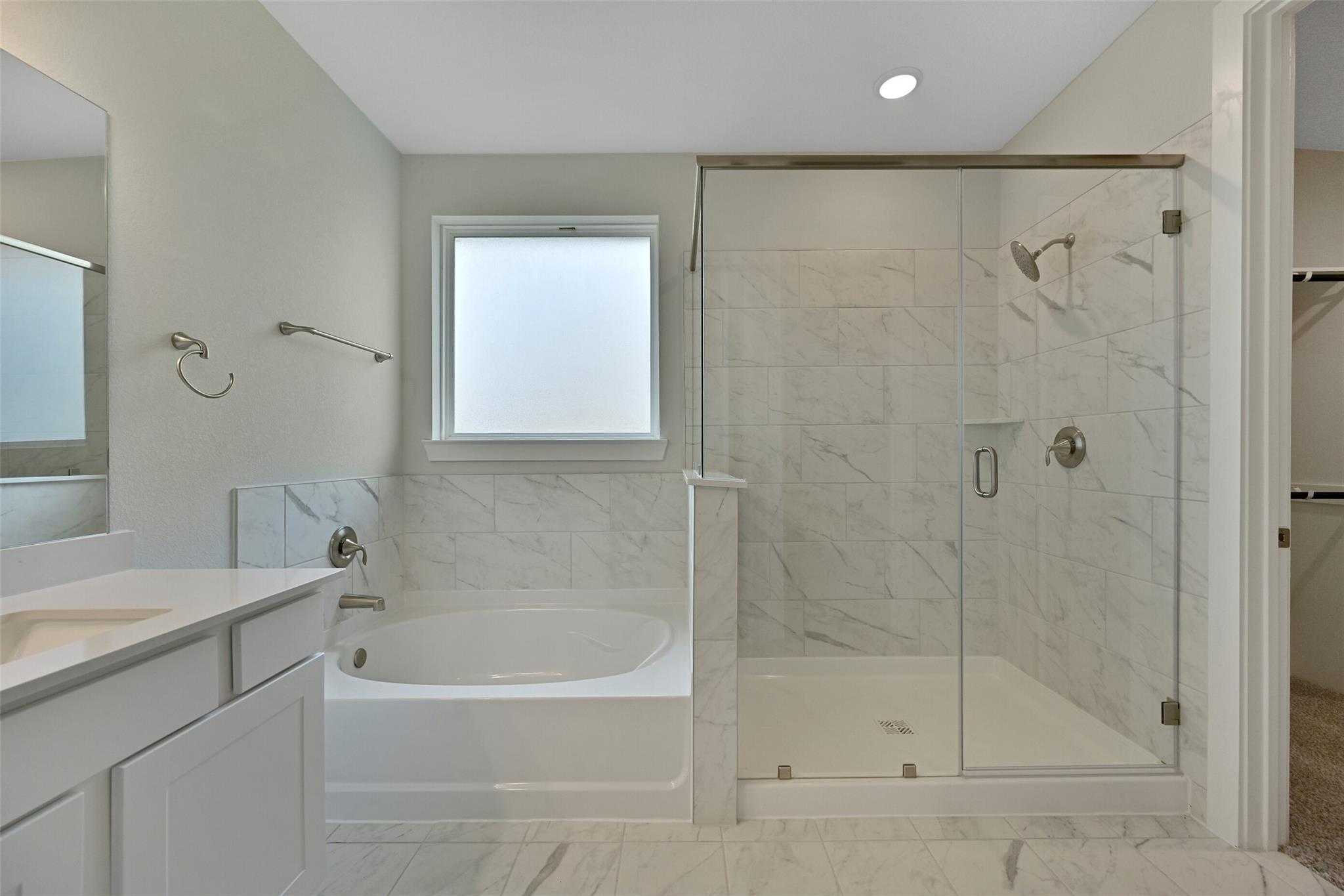 Modern master bathroom featuring freestanding tub, frameless glass shower, and marble-look tiles in Davidson Homes The Edward A, Lago Mar, Texas City