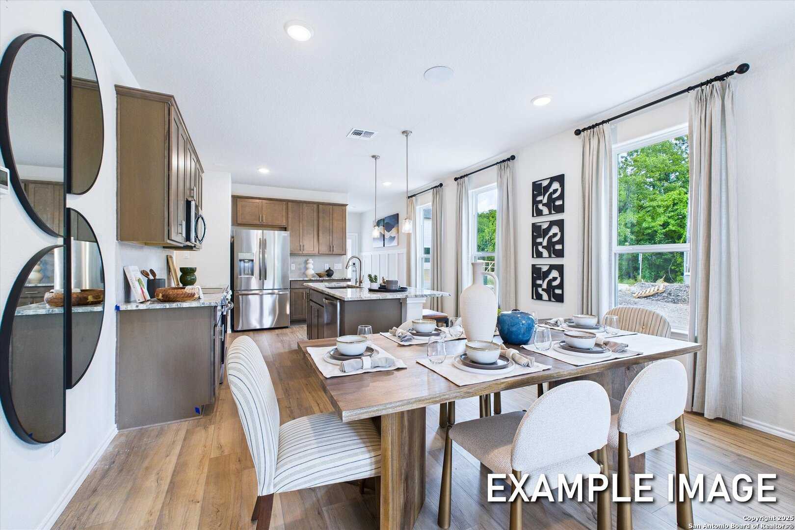 Modern open-concept kitchen and dining with stainless appliances, island, set table in The Gillian C, San Antonio, Texas