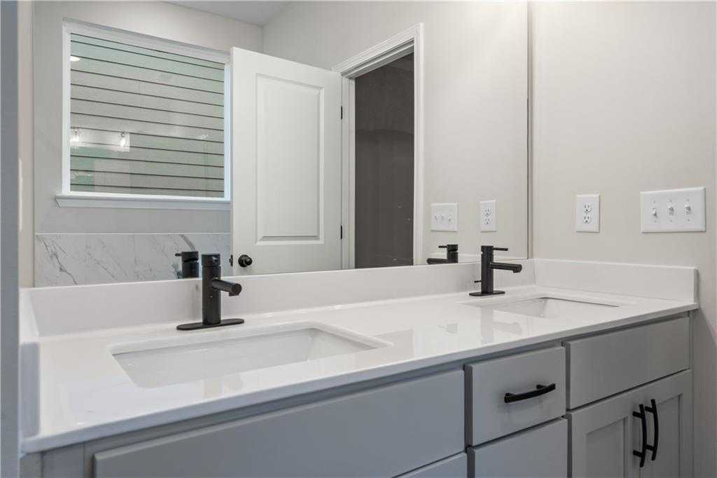 Modern double vanity with quartz counters, black faucets, and gray cabinets in The Daphne B bathroom, Davidson Homes, Loganville, GA