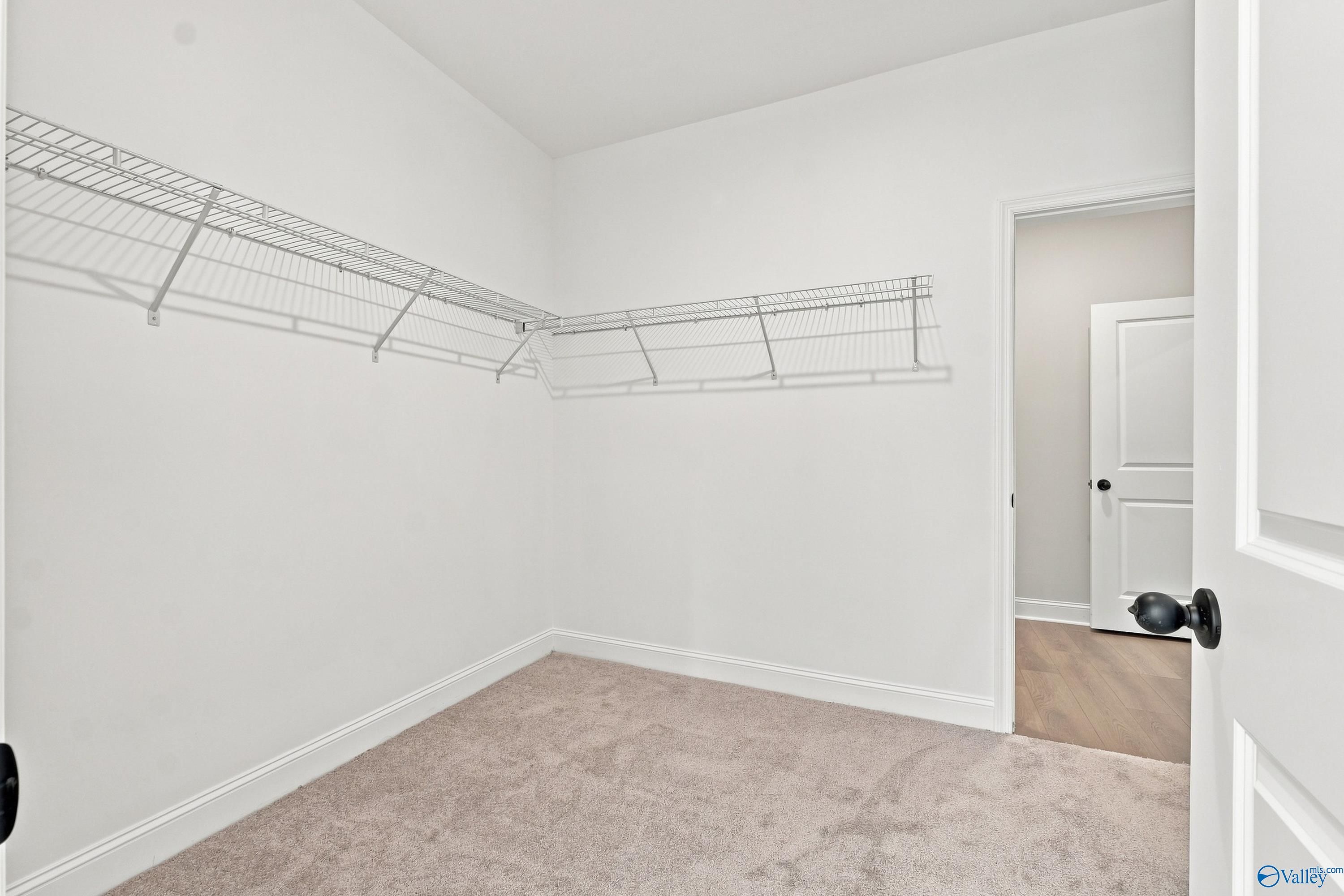 Walk-in closet with white wire shelving in The Rockford B floor plan at Kendall Downs, Toney, Alabama.