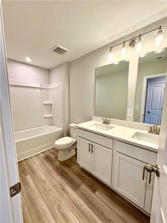 Modern white double vanity bathroom with soaking tub, mirrors, and luxury wood flooring in Davidson Homes The Monroe A, Emerson, GA