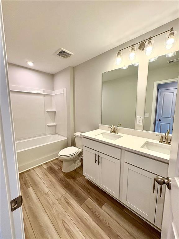 Modern white double vanity bathroom with soaking tub, mirrors, and luxury wood flooring in Davidson Homes The Monroe A, Emerson, GA