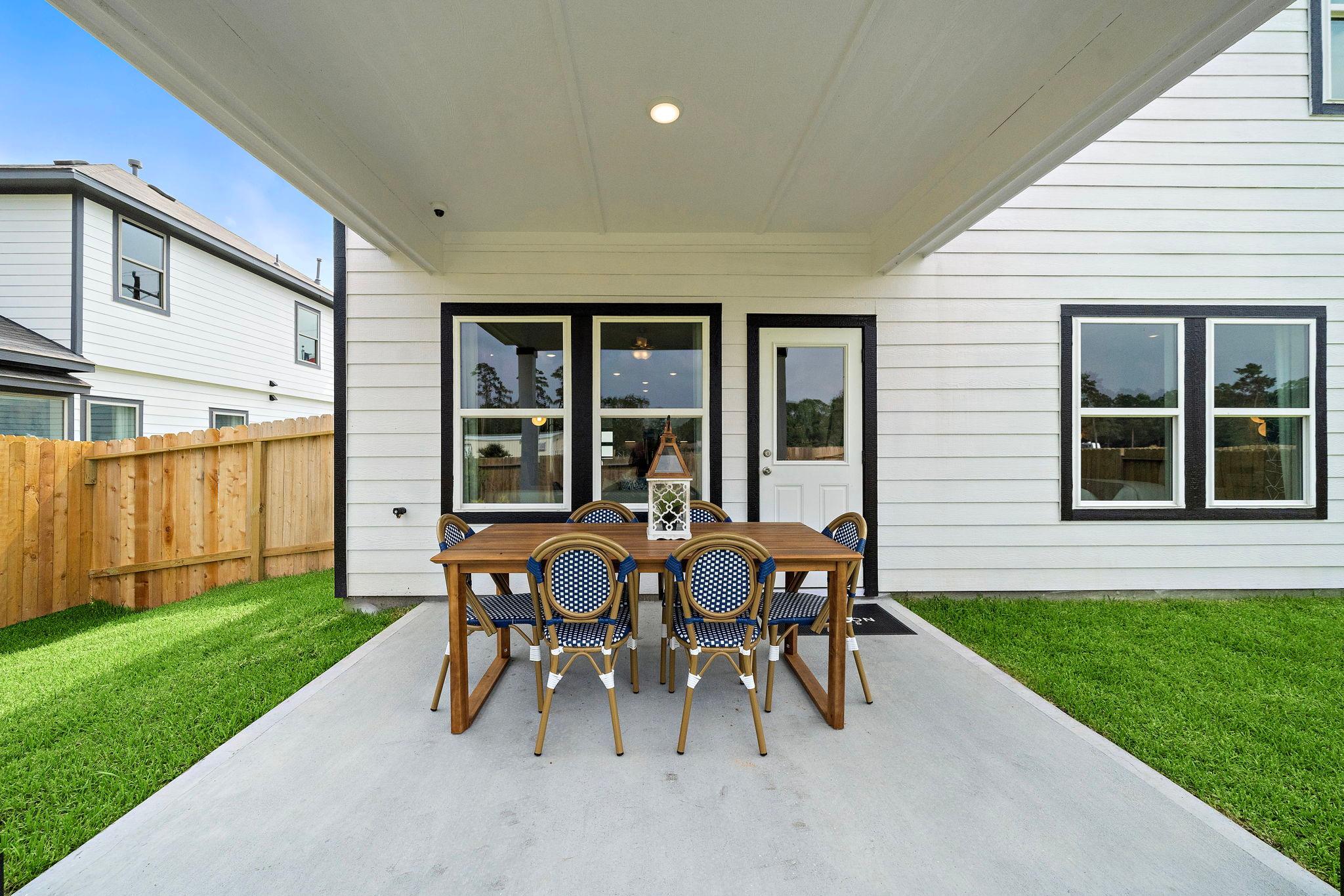 Covered patio with wooden dining table and blue upholstered chairs at Liberty Estates in Cleveland, Texas