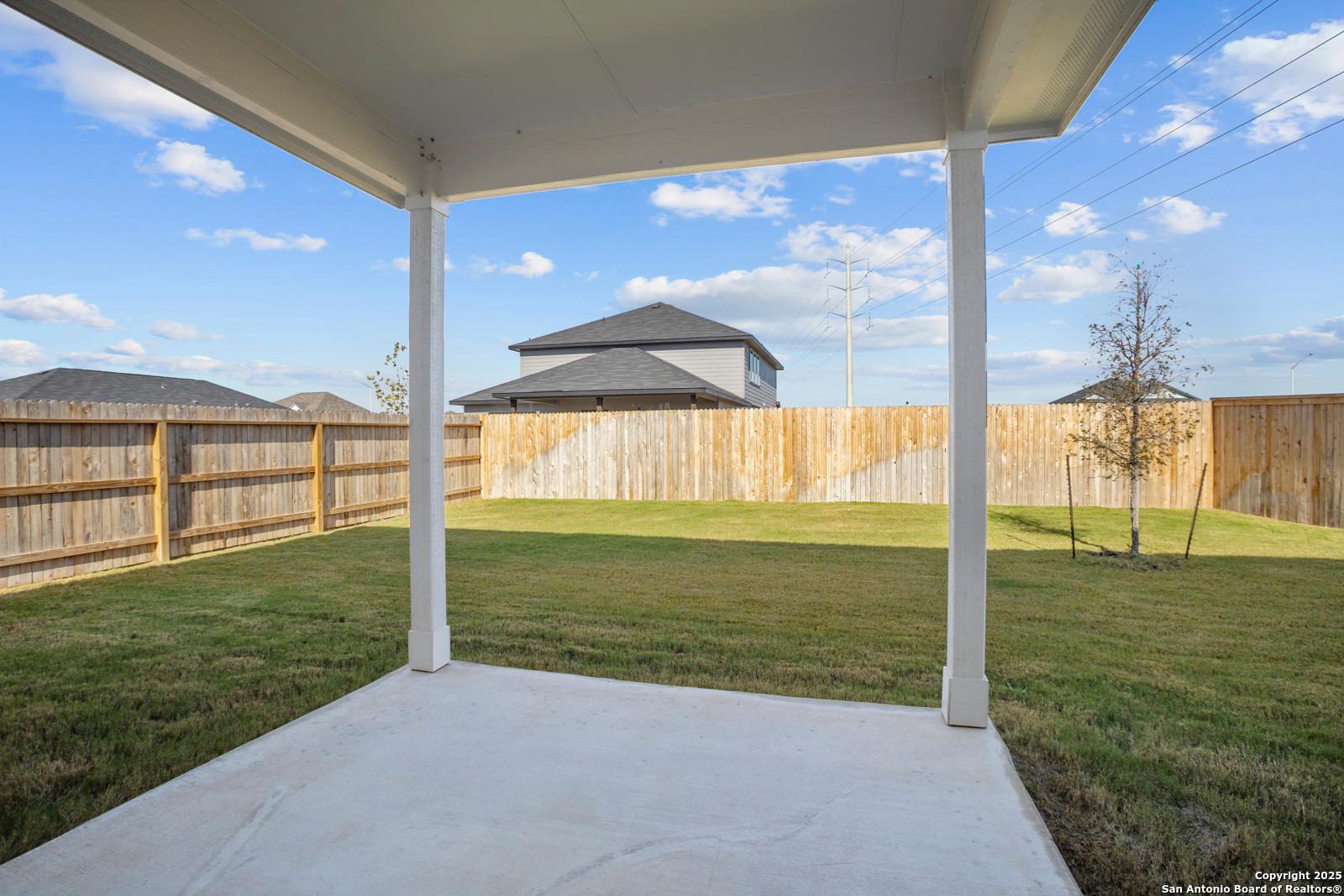 Covered patio with concrete slab overlooking lush green backyard and privacy fence in Davidson Homes The Douglas C, Seguin, Texas