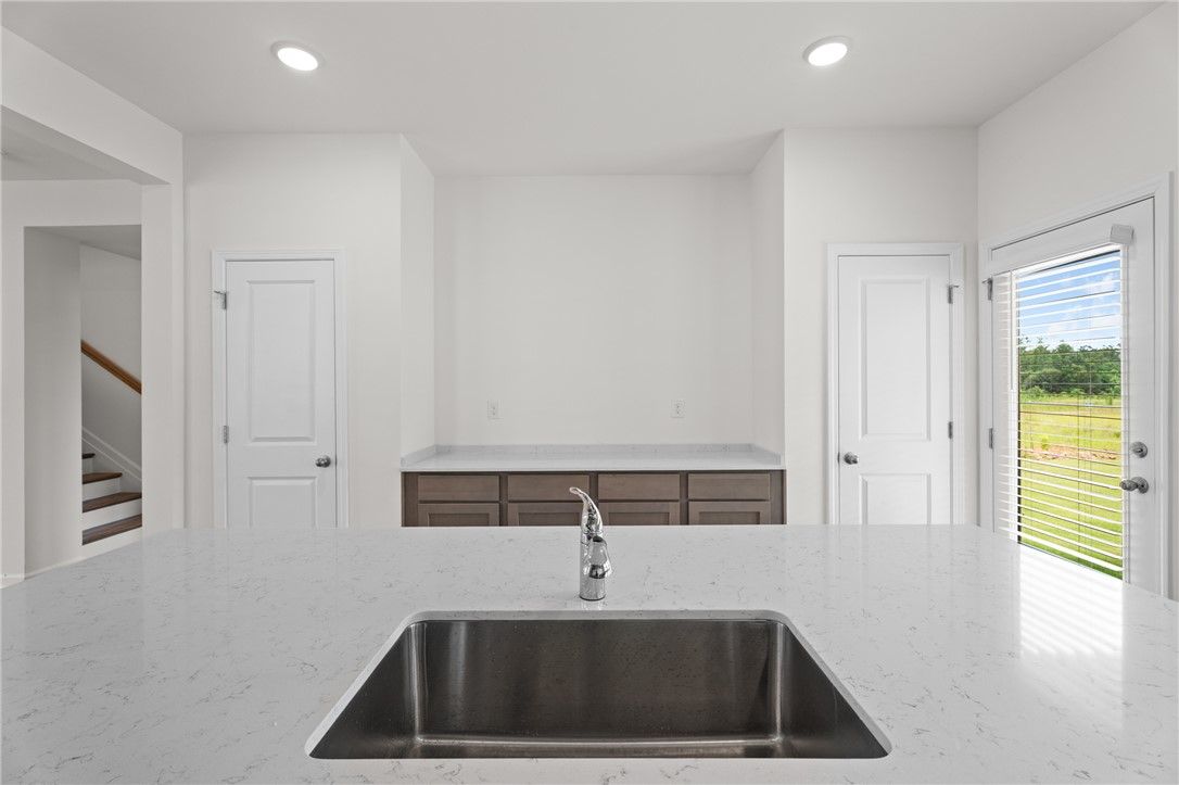 Modern kitchen island with quartz countertop and undermount sink in The Stella D floor plan by Evermore Homes in Cusseta.