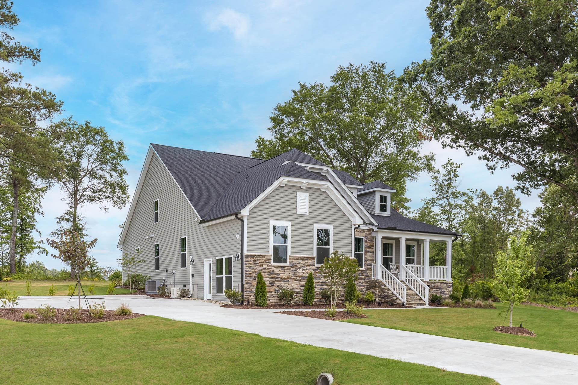 Modern craftsman-style home exterior at Weatherford East in Angier, NC with wraparound porch, stone accents, and lush green lawn