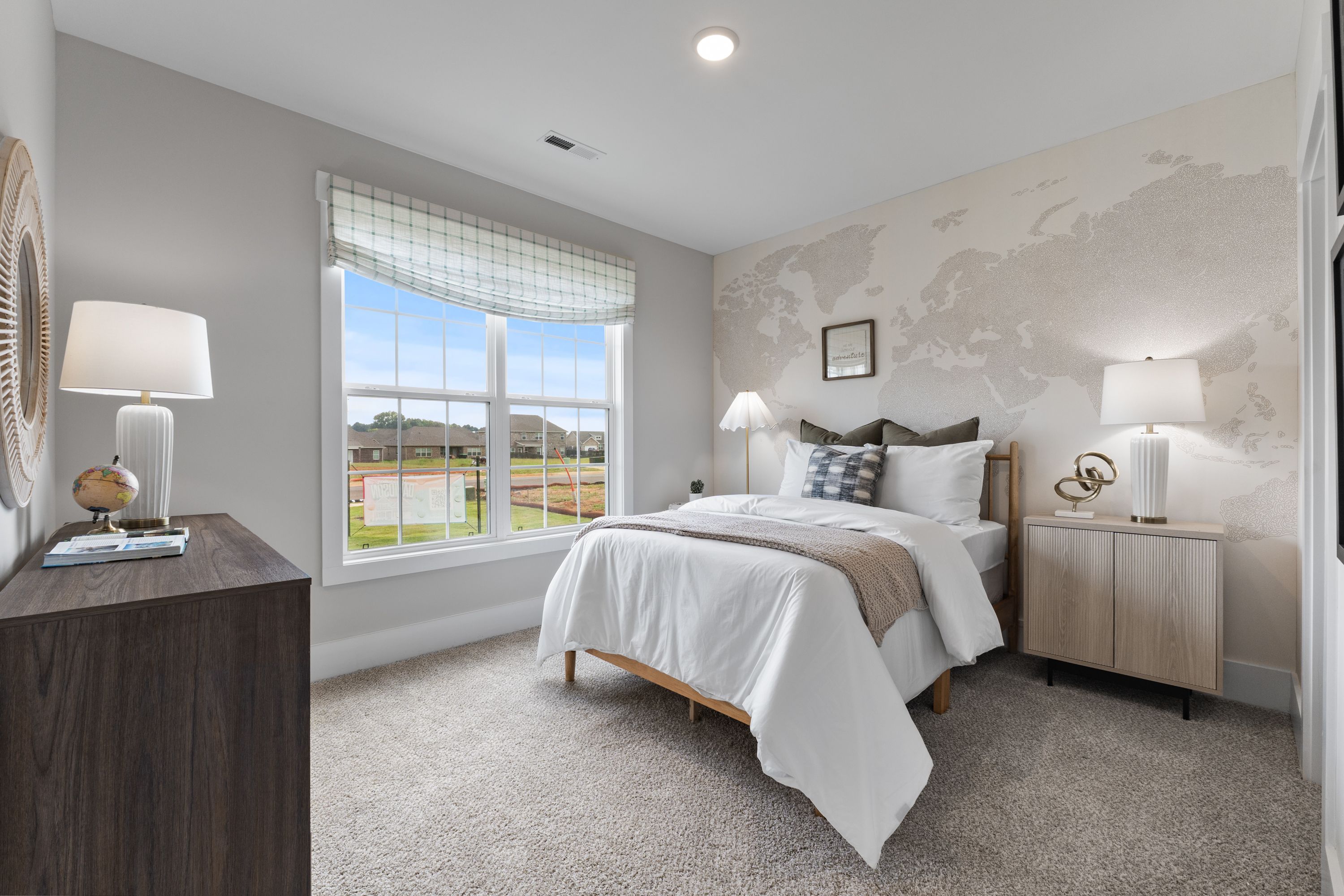 Cozy bedroom at River Road Estates in Decatur Alabama with world map wall, plush bed, and scenic field view through window