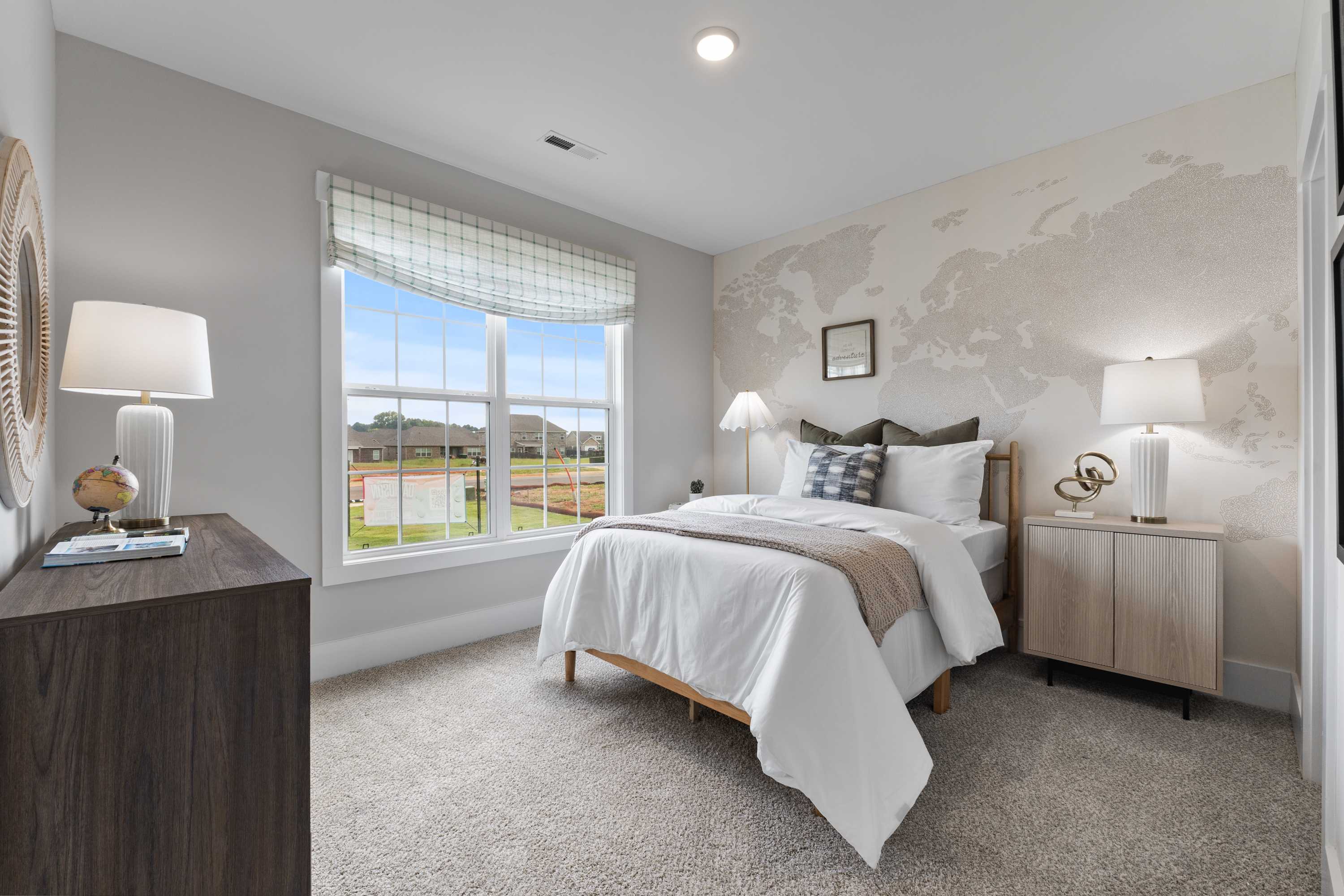 Cozy bedroom at River Road Estates in Decatur Alabama with world map wall, plush bed, and scenic field view through window