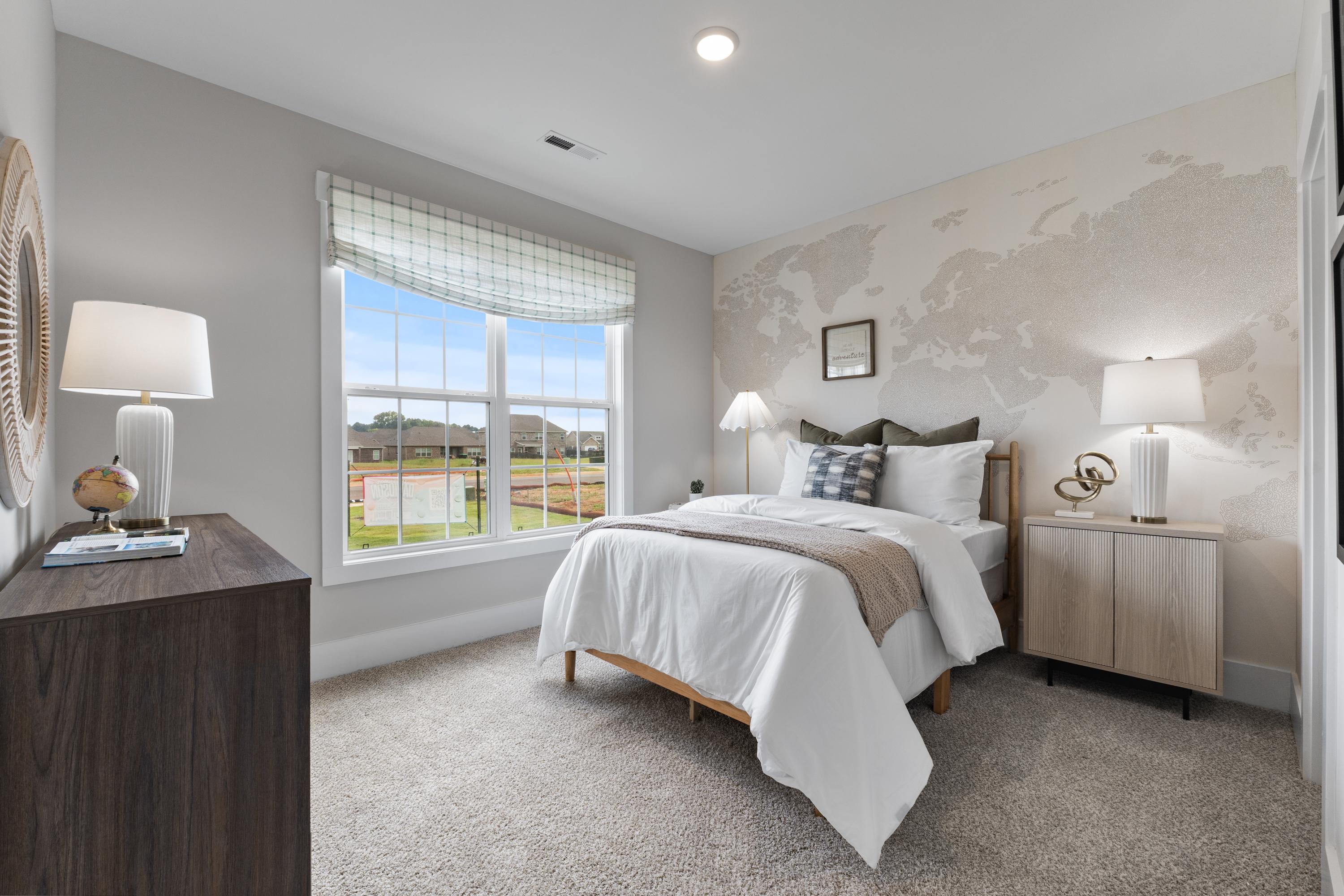 Cozy bedroom at River Road Estates in Decatur Alabama with world map wall, plush bed, and scenic field view through window