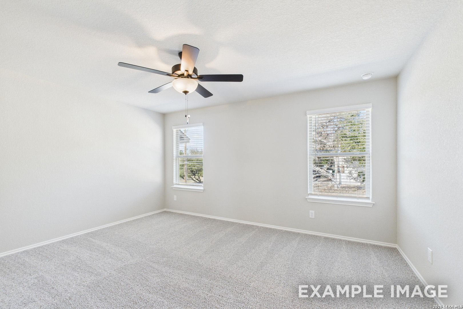 Bright, carpeted bedroom with ceiling fan and natural light in The Charlotte B floor plan by Davidson Homes in San Antonio.