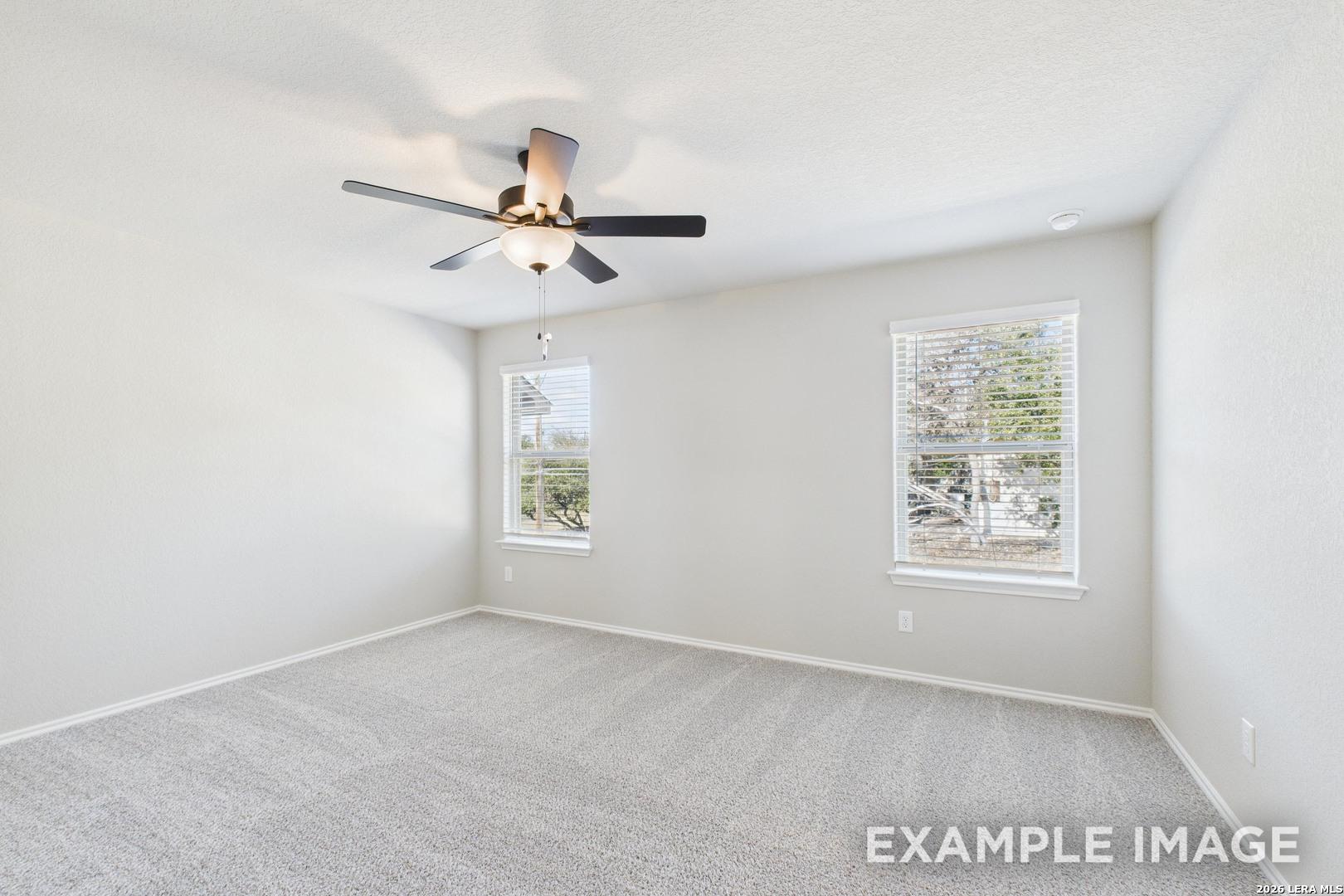 Bright, carpeted bedroom with ceiling fan and natural light in The Charlotte B floor plan by Davidson Homes in San Antonio.
