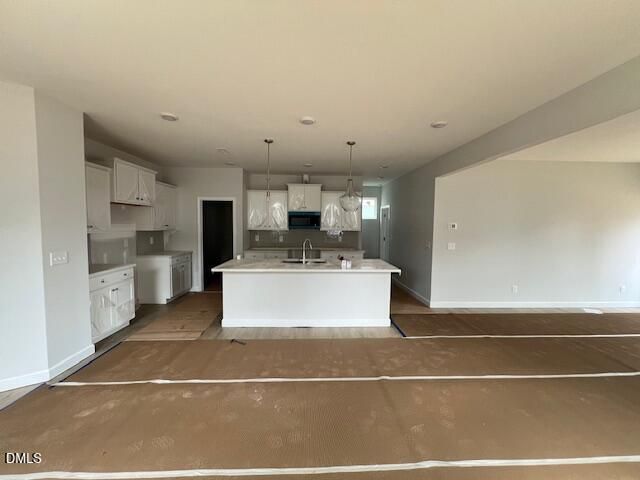 Modern open-concept kitchen featuring white island, cabinets, and stainless appliances in The Adalynn B by Davidson Homes, Lillington, NC