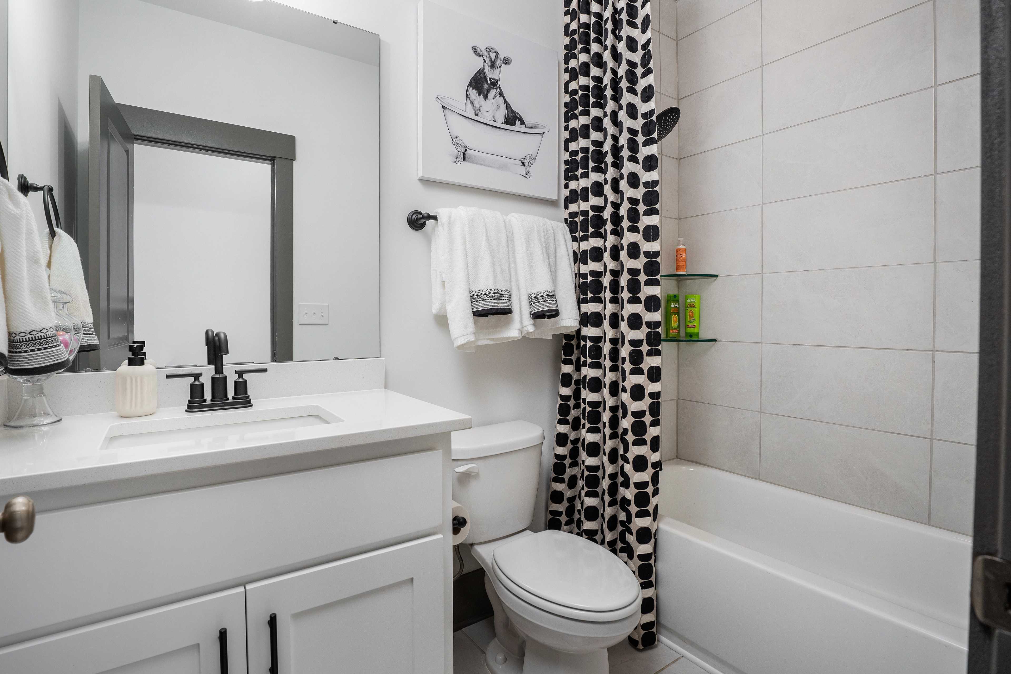 Contemporary bathroom at Barnett's Crossing in Madison, Alabama with white vanity, polka dot shower curtain, and bathtub