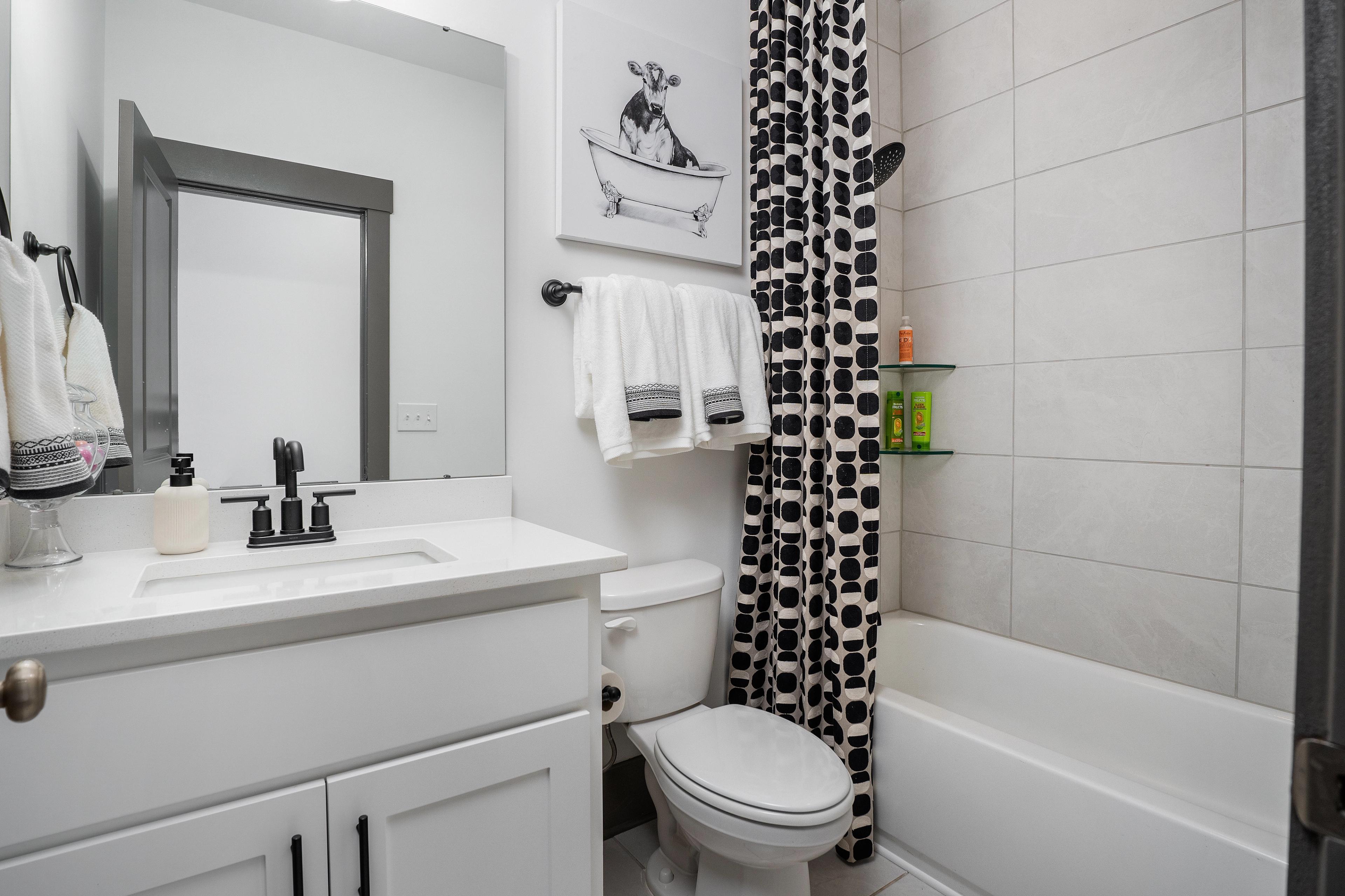 Contemporary bathroom at Barnett's Crossing in Madison, Alabama with white vanity, polka dot shower curtain, and bathtub