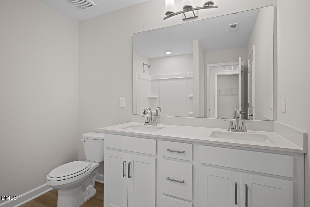 Modern bathroom with double vanity, white cabinetry, and large mirror in The Chestnut floor plan at Wendell Ridge.