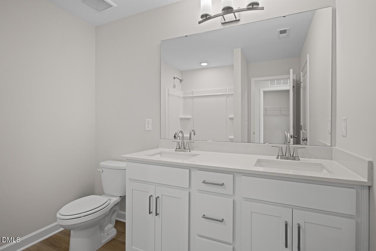 Modern bathroom with double vanity, white cabinetry, and large mirror in The Chestnut floor plan at Wendell Ridge.