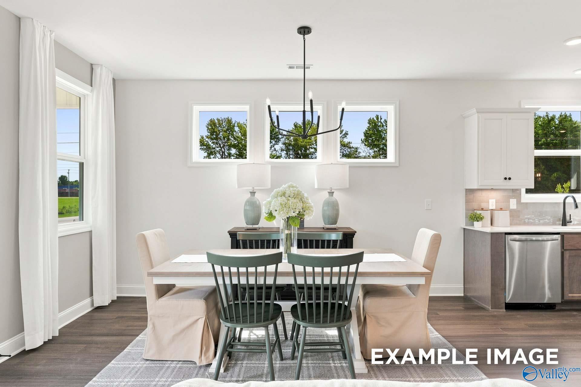 Bright dining area with white farmhouse table, green spindle chairs, and black chandelier in Davidson Homes Ashport G, New Market, AL