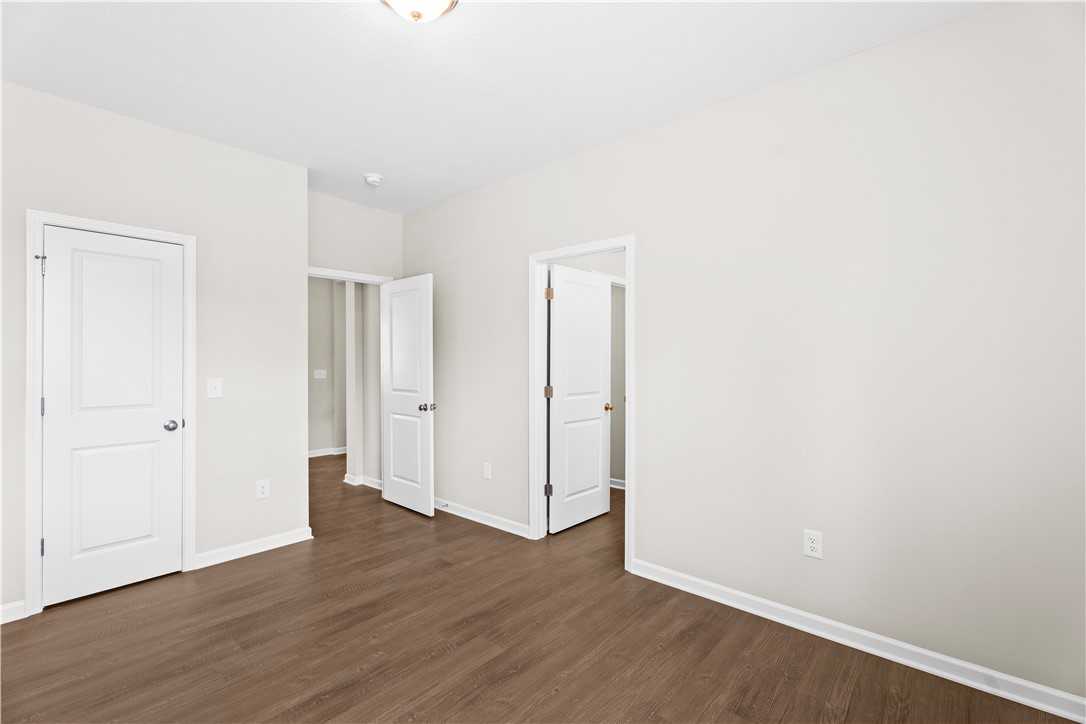 Bright hallway with white doors, beige walls, and hardwood floors in 4-bedroom The Orion home, Cusseta, Alabama