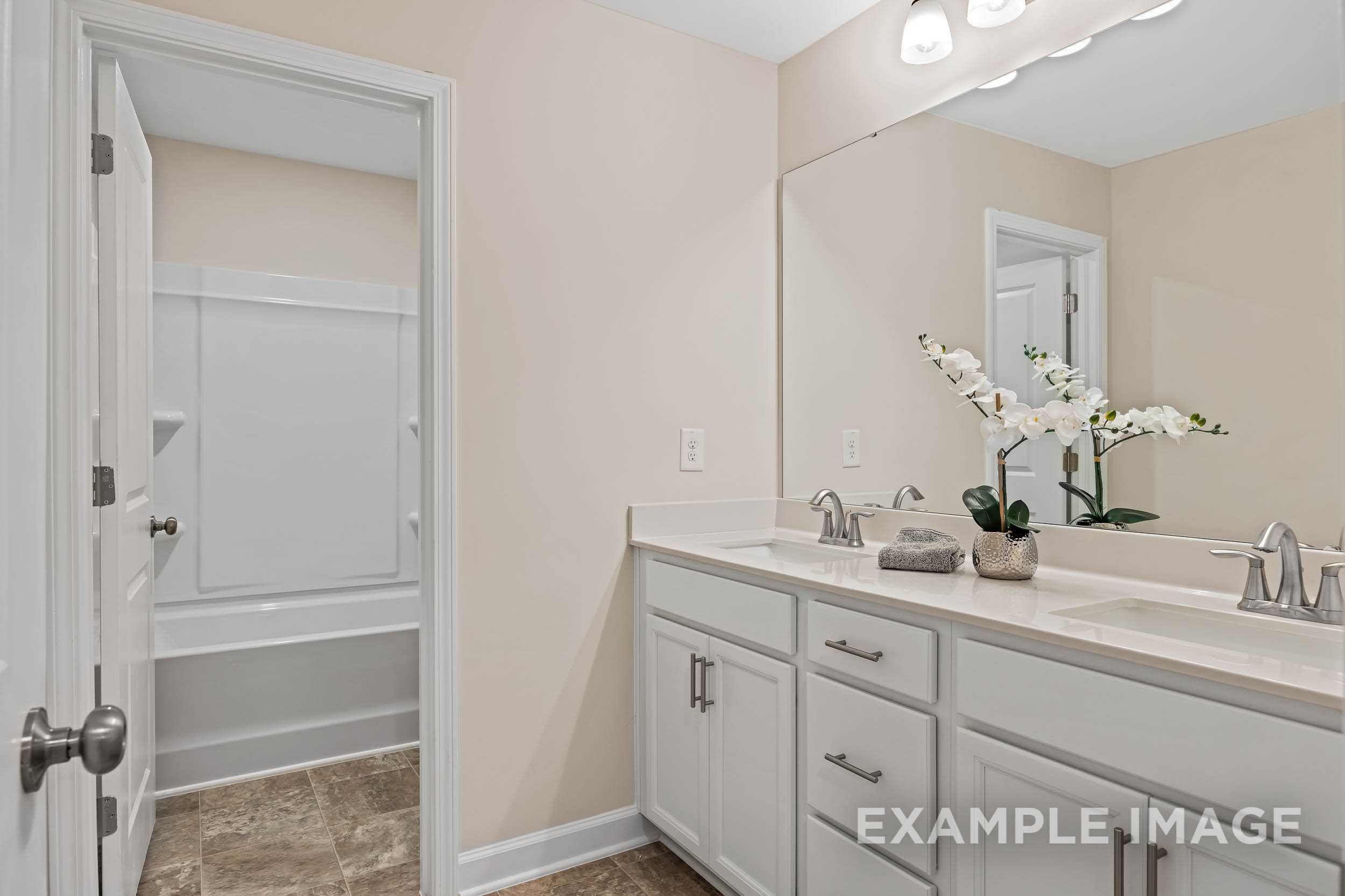 Spacious master bathroom in The Preston A with double vanity, soaking tub, neutral walls, and orchid accents