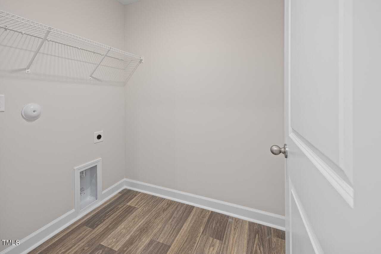 Functional laundry room with utility sink, wire shelving, and wood-look flooring in Davidson Homes The Graham, Fuquay-Varina, NC