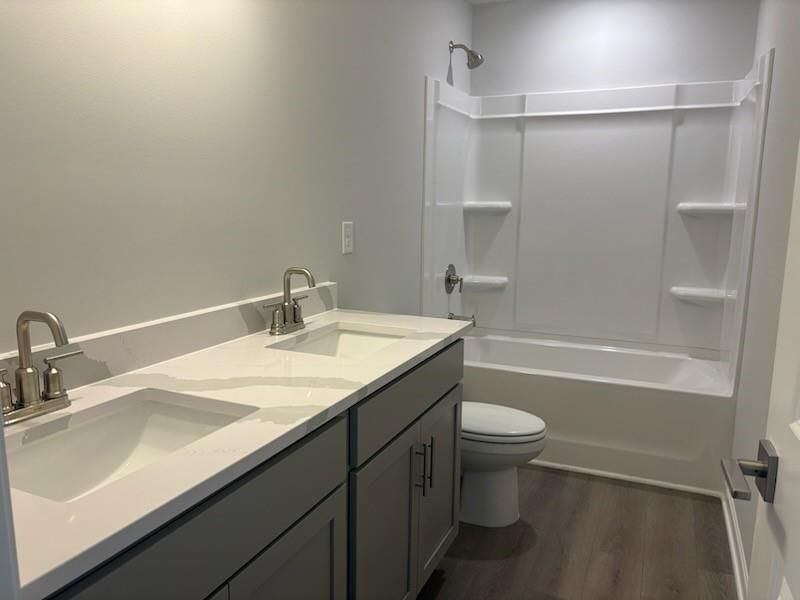 Modern bathroom with double vanity, white quartz counters, gray cabinets, tub/shower combo in Davidson Homes The Rabun A, Winder GA