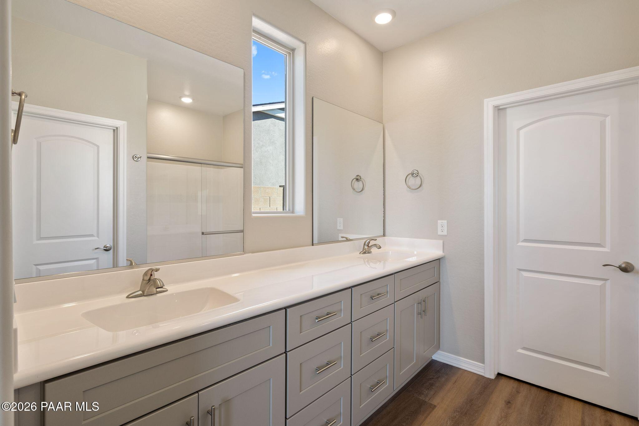 Modern master bathroom featuring double vanity with gray cabinets, white quartz countertop, and frameless shower in Davidson Homes The Frontier A, Prescott Valley, Arizona