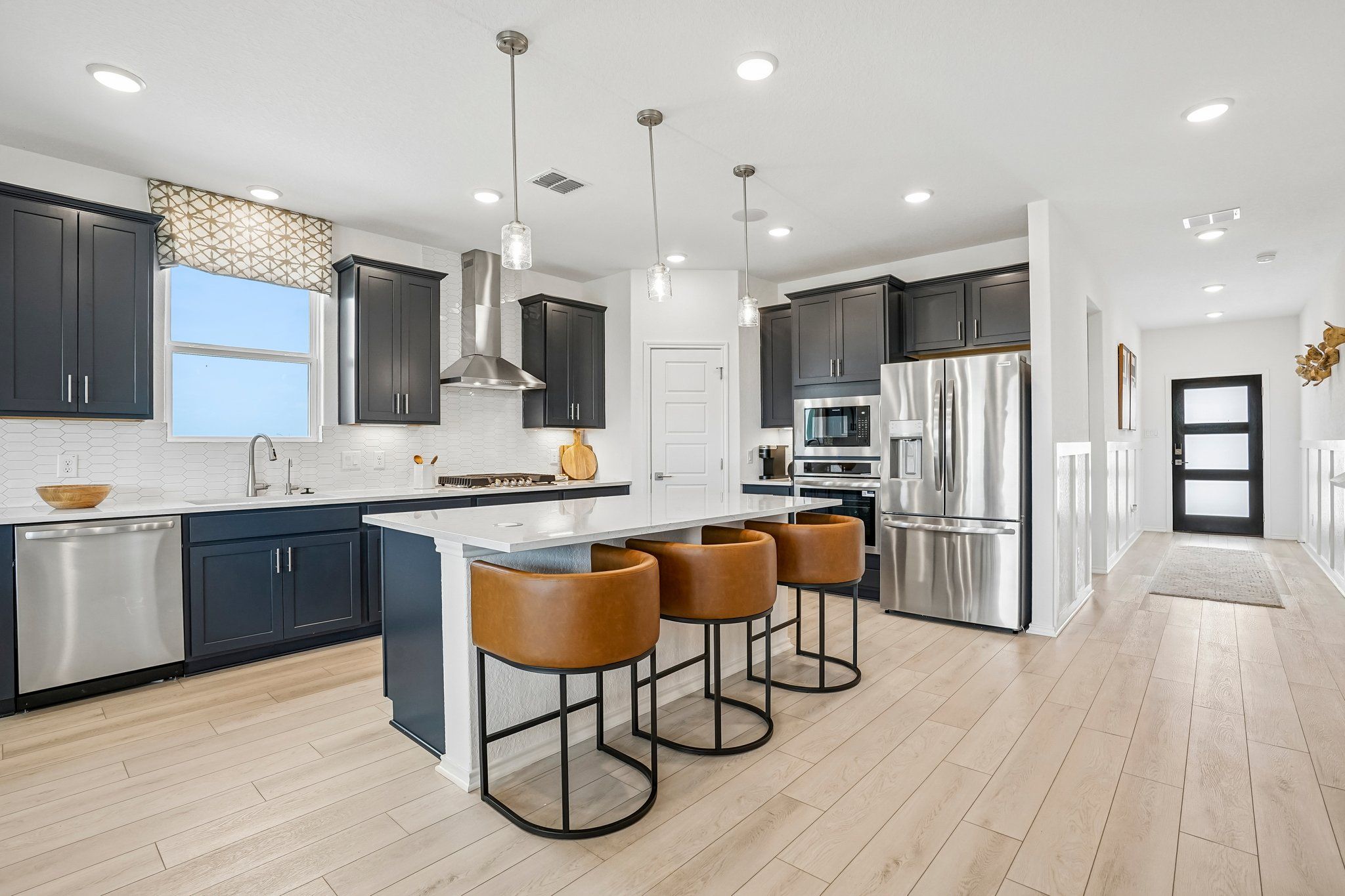 Modern kitchen at Morgan Meadows in San Antonio with dark cabinets, stainless steel appliances, and a leather bar stool island.