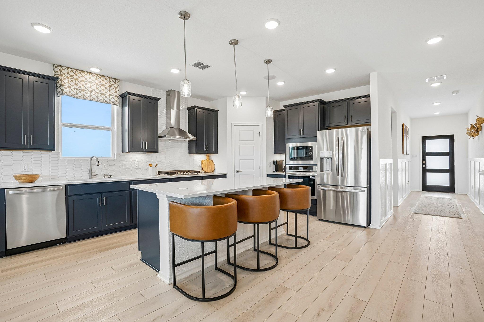 Modern kitchen at Morgan Meadows in San Antonio with dark cabinets, stainless steel appliances, and a leather bar stool island.