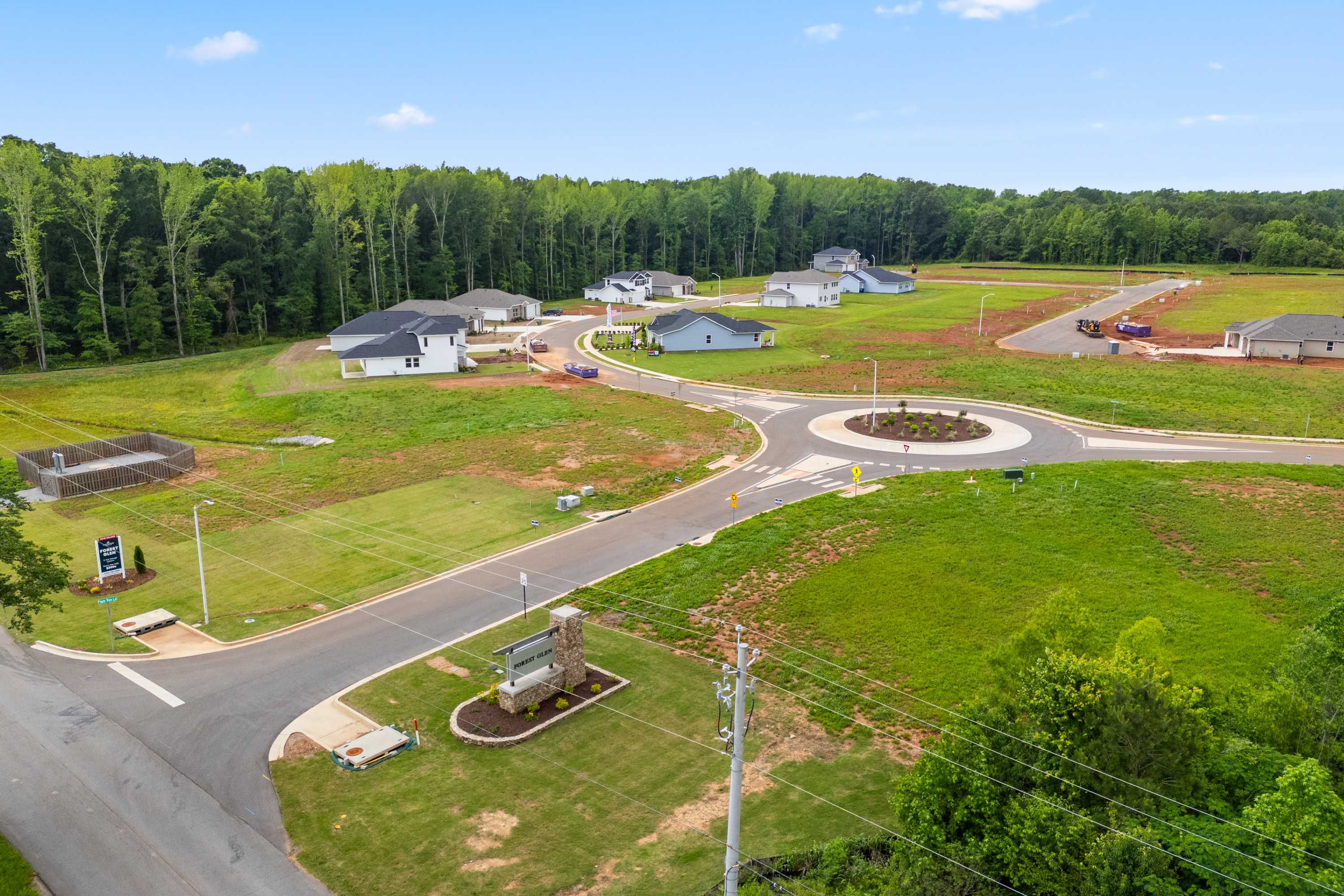 Aerial view of new Davidson Homes under construction in Forest Glen, Hazel Green Alabama with roundabout entrance and wooded surroundings