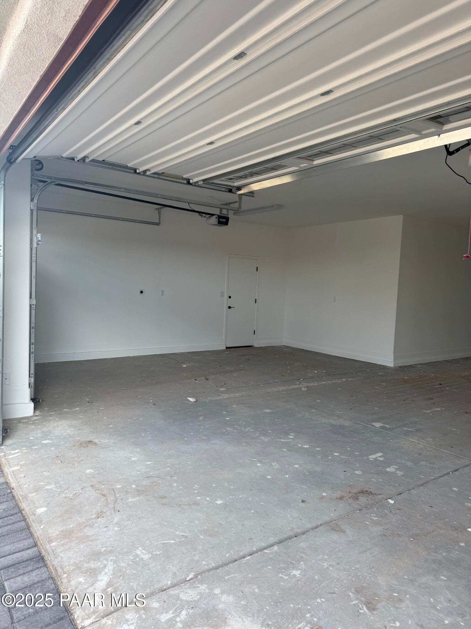 Spacious 4-car garage with open doors, white walls, and concrete floor in Evermore Homes The Sunrise A, Prescott Valley, Arizona