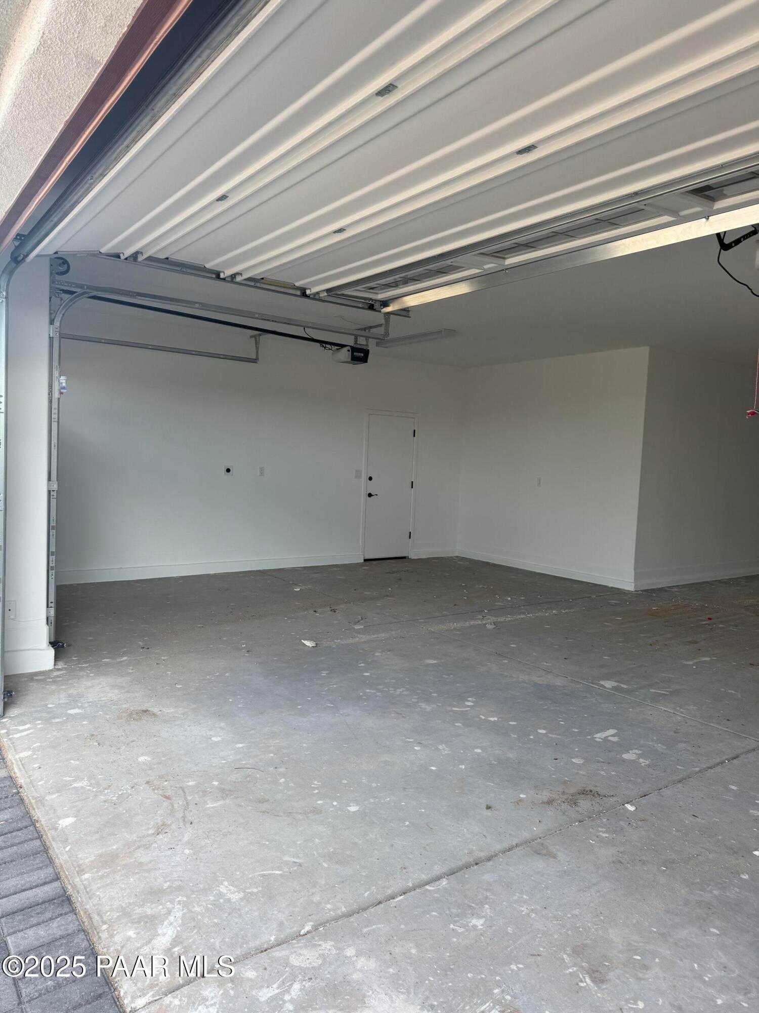 Spacious 4-car garage with open doors, white walls, and concrete floor in Evermore Homes The Sunrise A, Prescott Valley, Arizona