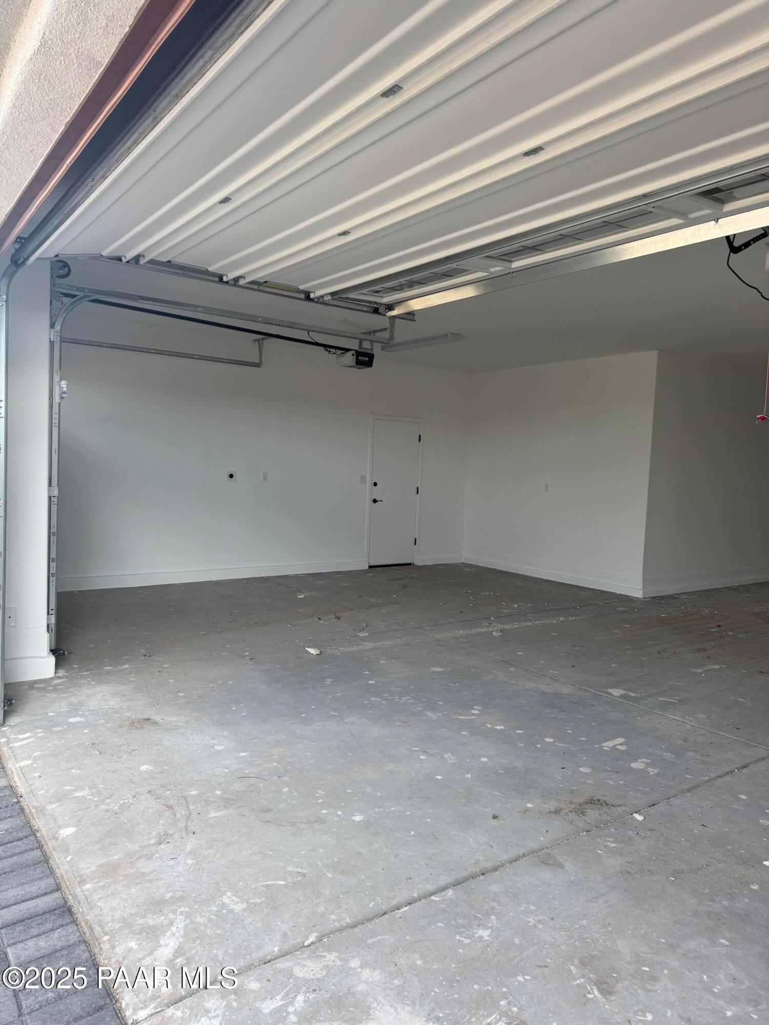 Spacious 4-car garage with open doors, white walls, and concrete floor in Evermore Homes The Sunrise A, Prescott Valley, Arizona