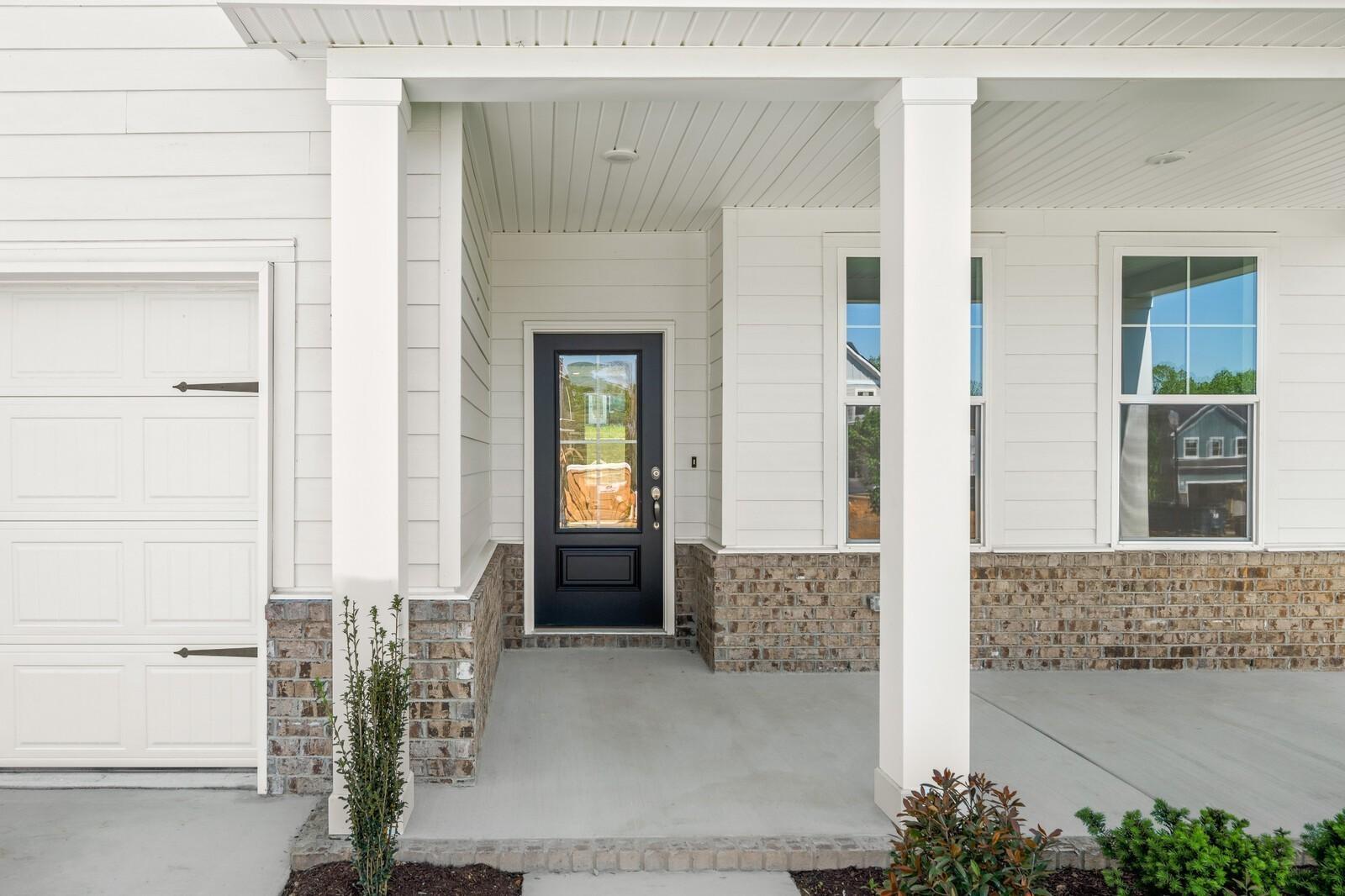 Covered front porch with black door and brick accents on The Henry C floor plan by Davidson Homes in Calista Farms.